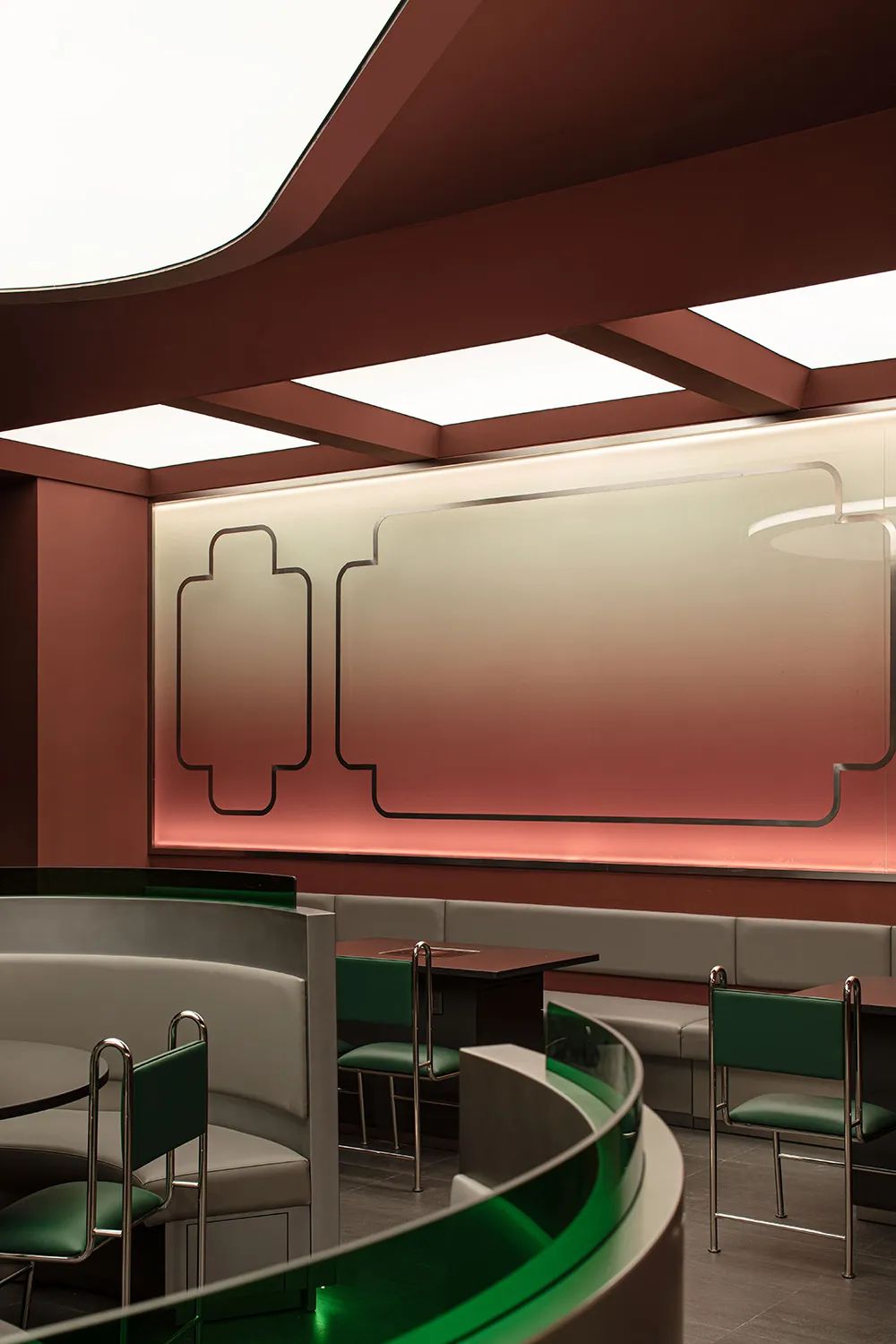 A modern restaurant interior with metallic tables, glass fixtures, and leather seating.