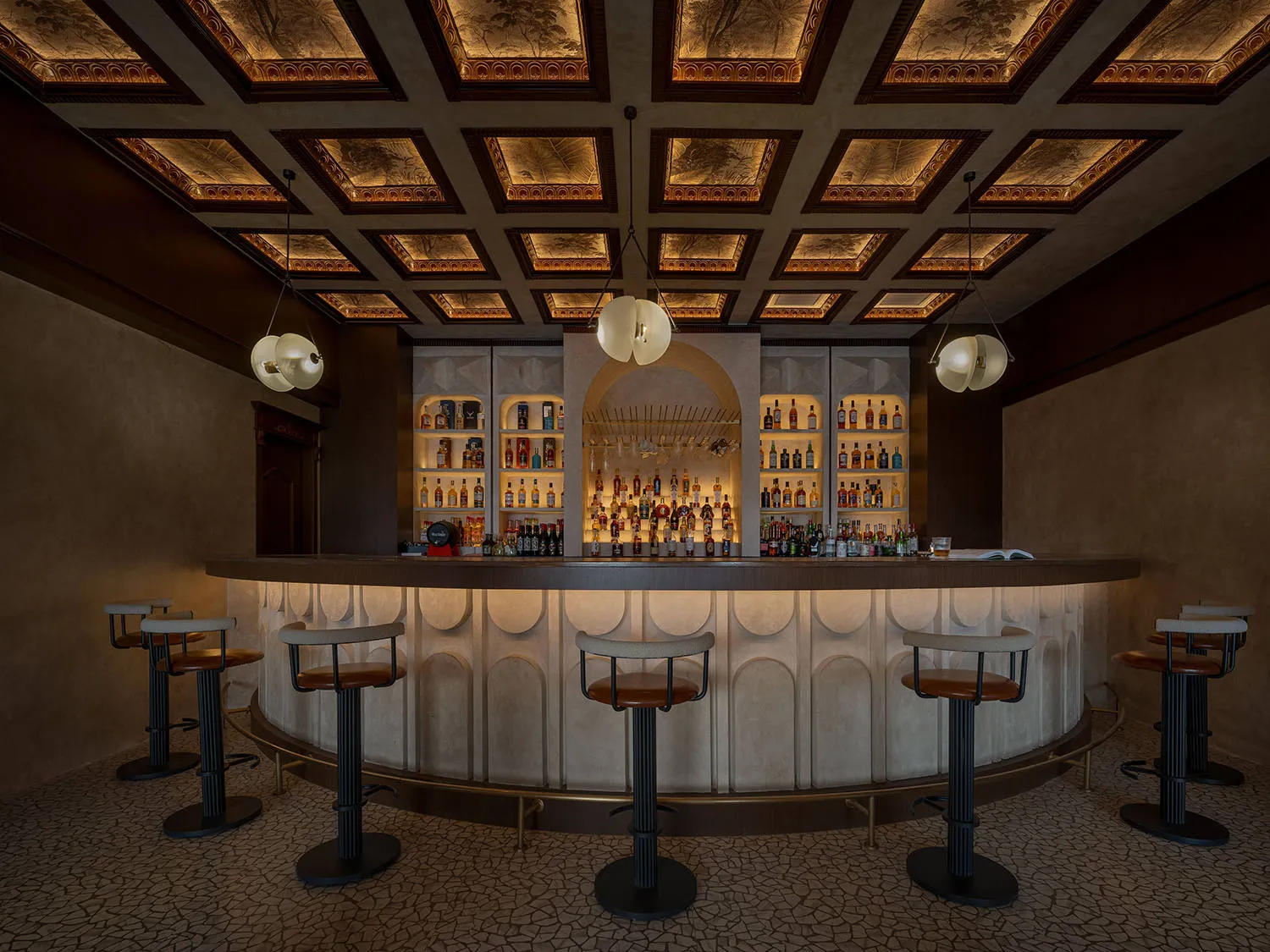 A luxury bar interior featuring a sleek, modern concrete counter with bar stools, illuminated shelves, and a sophisticated ce