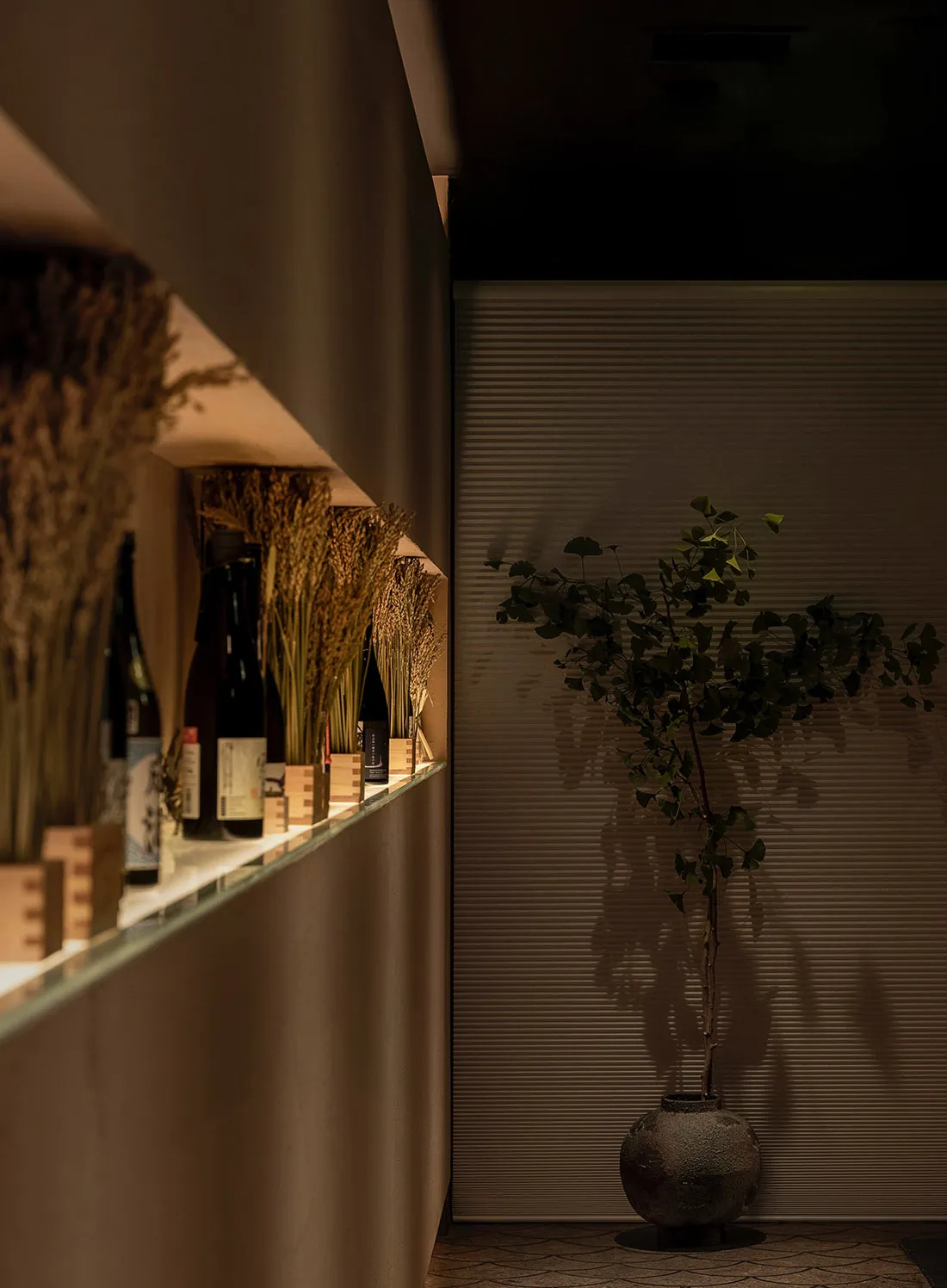 現代簡約餐廳室內，搭配木質元素、擺放酒瓶的層架，以及綠色植物。