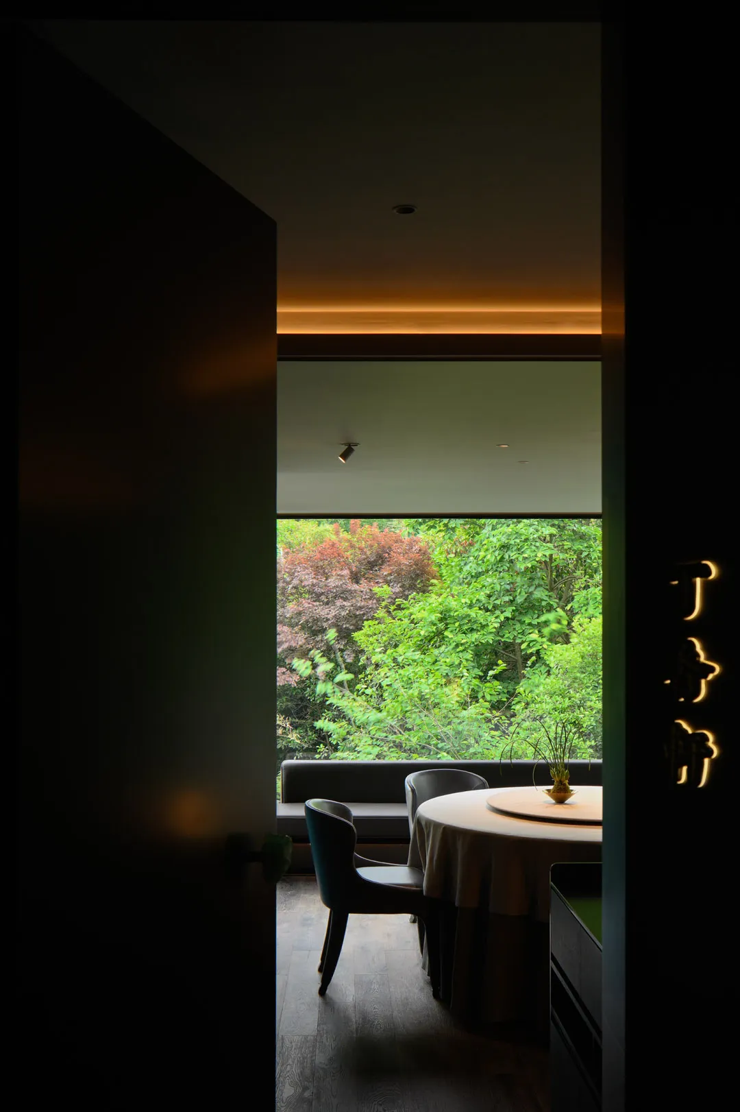 A modern, minimalist restaurant interior with a circular table and chairs, illuminated by soft, ambient lighting.