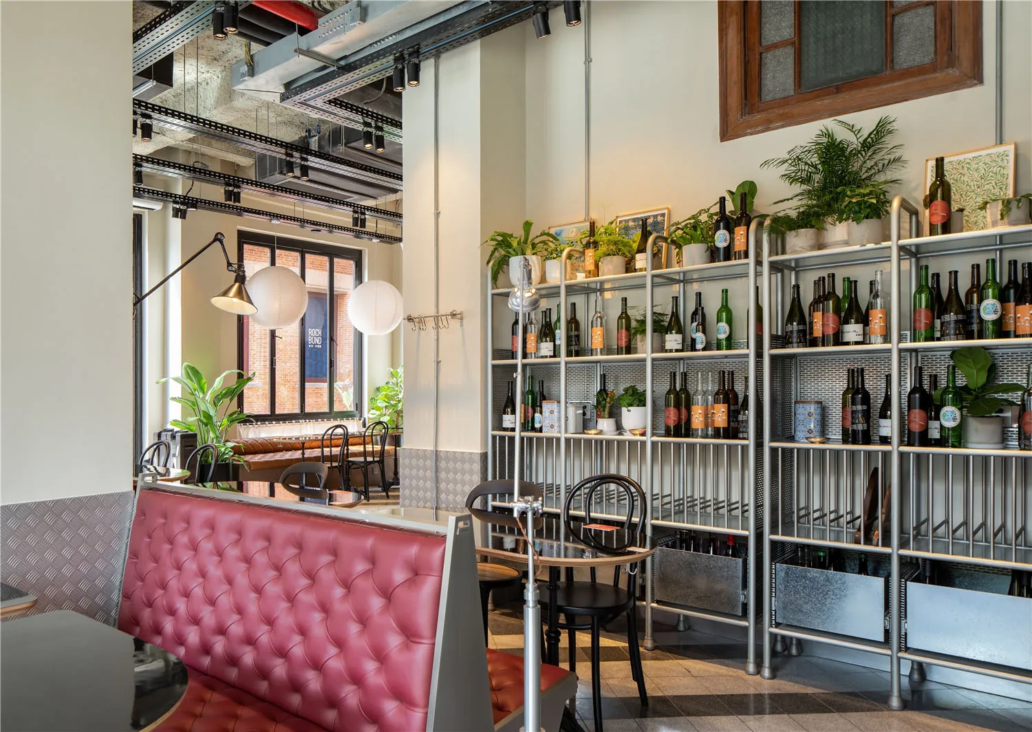 A modern restaurant interior featuring metal shelving and potted plants.