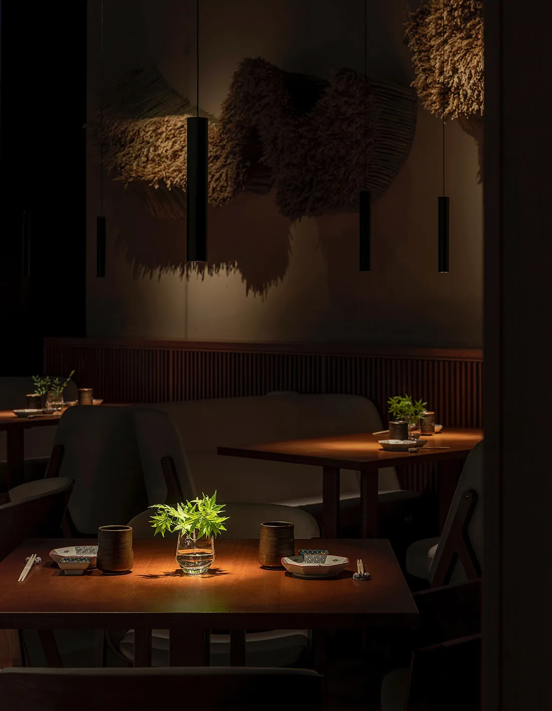 A modern restaurant with wooden tables and chairs, featuring a warm and inviting ambiance with hanging planters and natural l