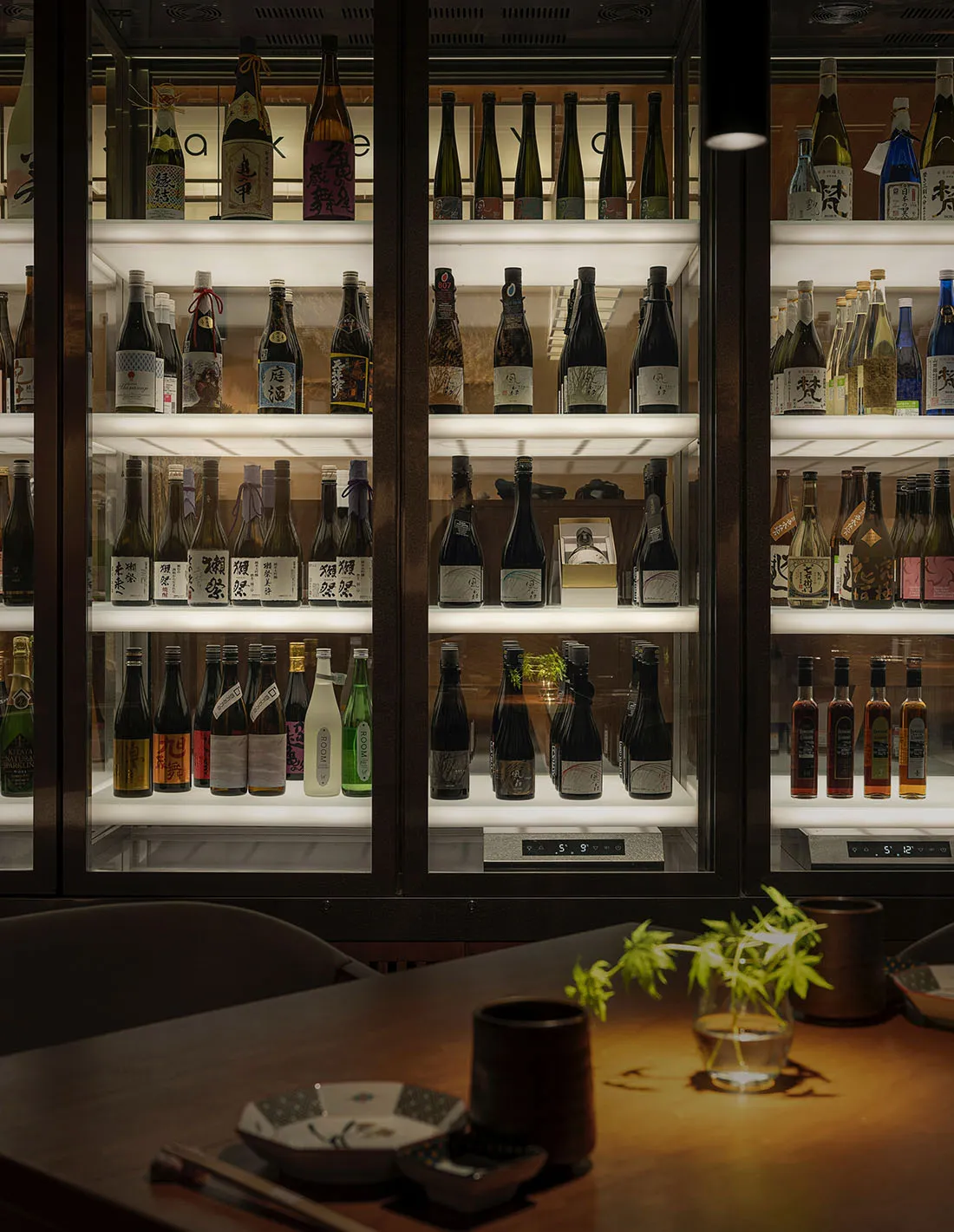 Glass bottles of alcohol arranged on shelves in a wine bar setting.