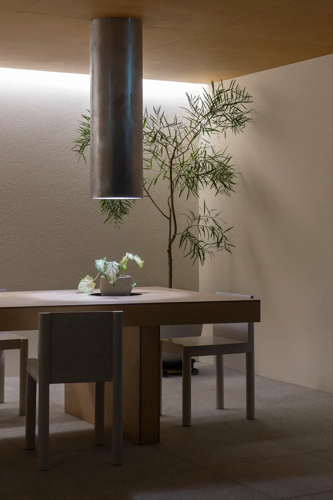 A modern minimalist dining room featuring a wooden table and chairs.