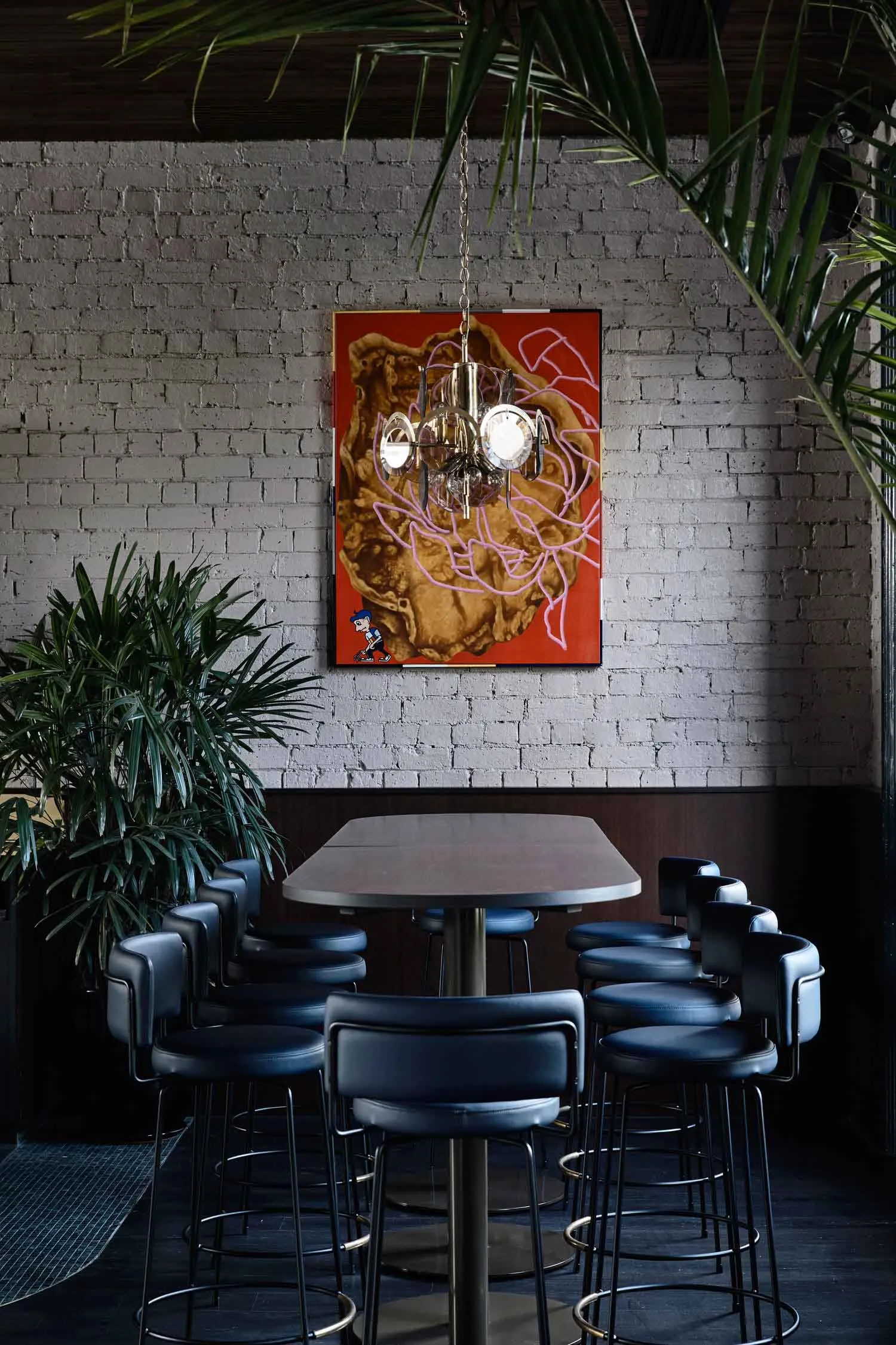 Industrial-style bar with metal stools, leather seating, and wooden table and chairs.