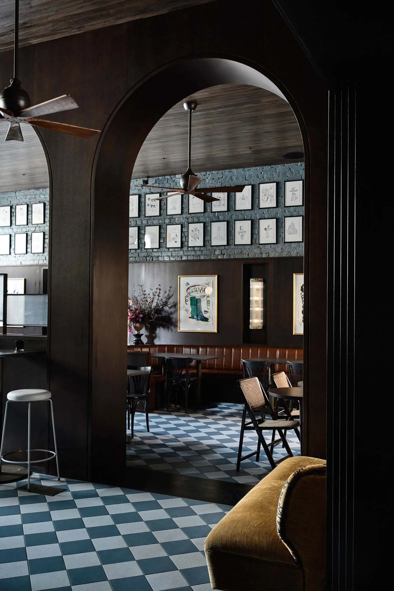 Industrial restaurant interior with brick walls, brown leather booths, wooden tables, and metal accents.