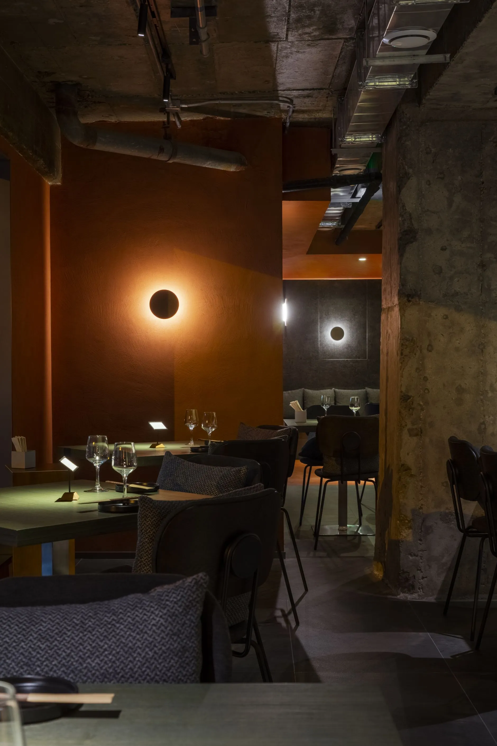 Industrial-style restaurant interior with concrete walls, wooden tables, and metal accents.