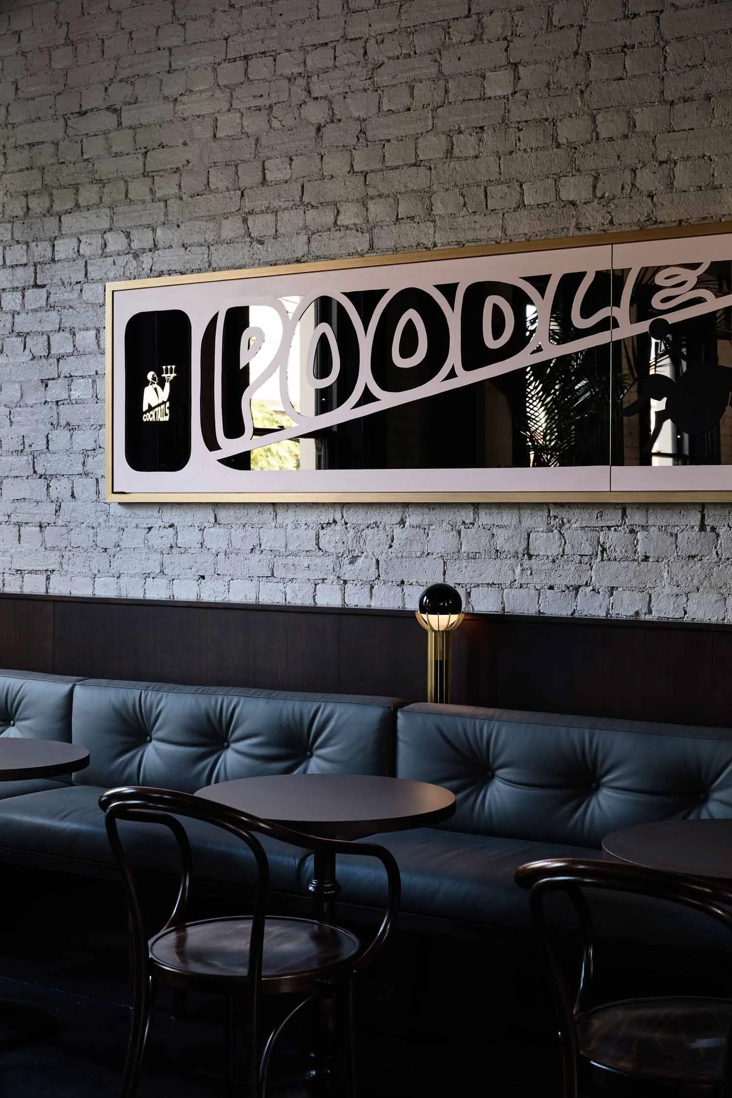 Industrial style restaurant interior with metal sign, leather seating, and brick wall