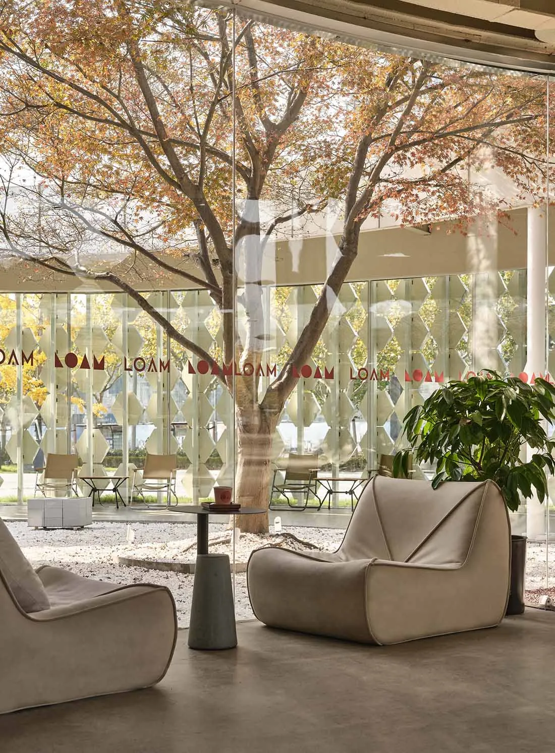 A modern lobby area with glass walls and furniture, featuring a relaxing seating area with comfortable sofas and a small tabl