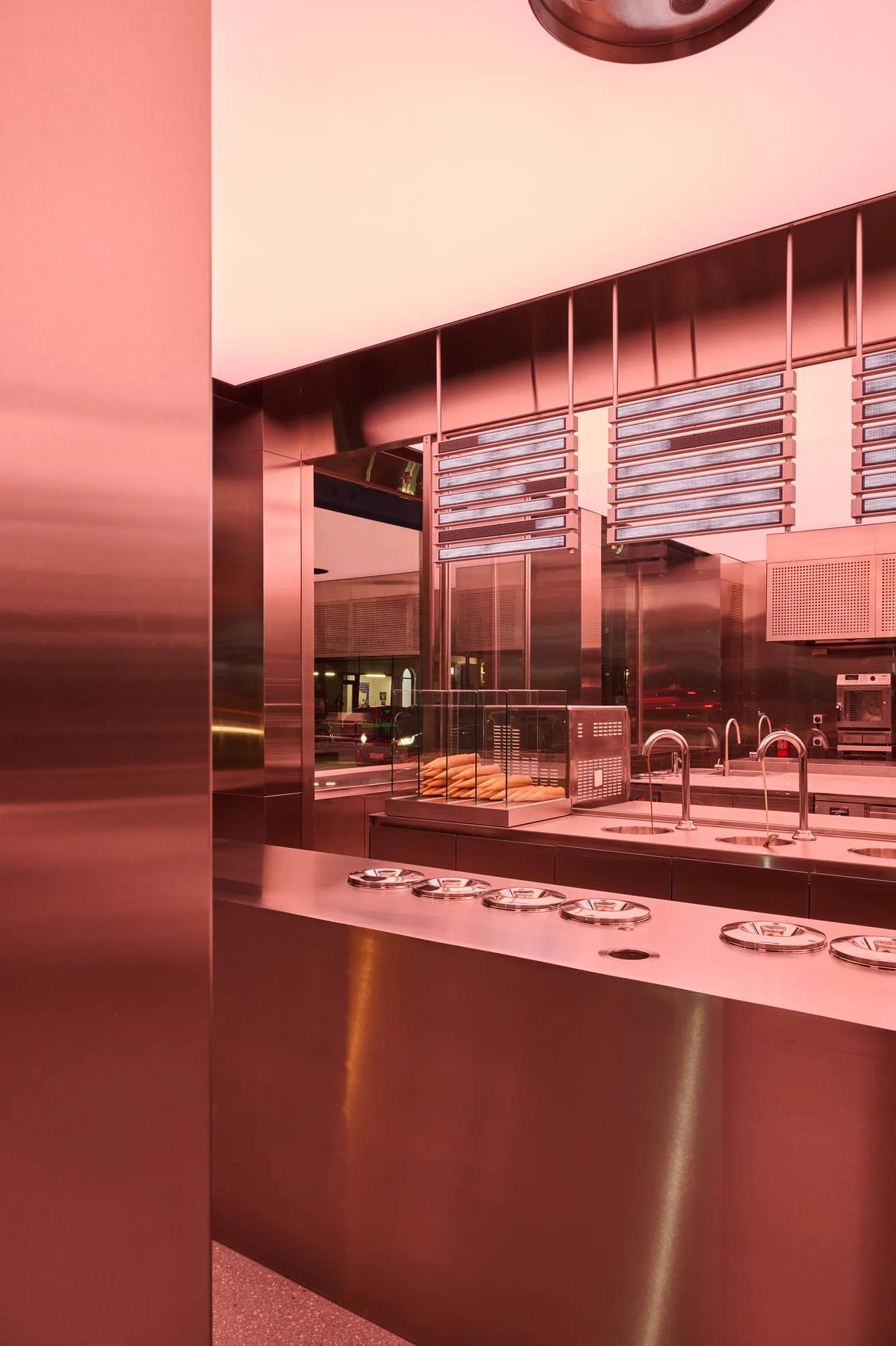 A modern restaurant kitchen with metallic surfaces and stainless steel countertops.