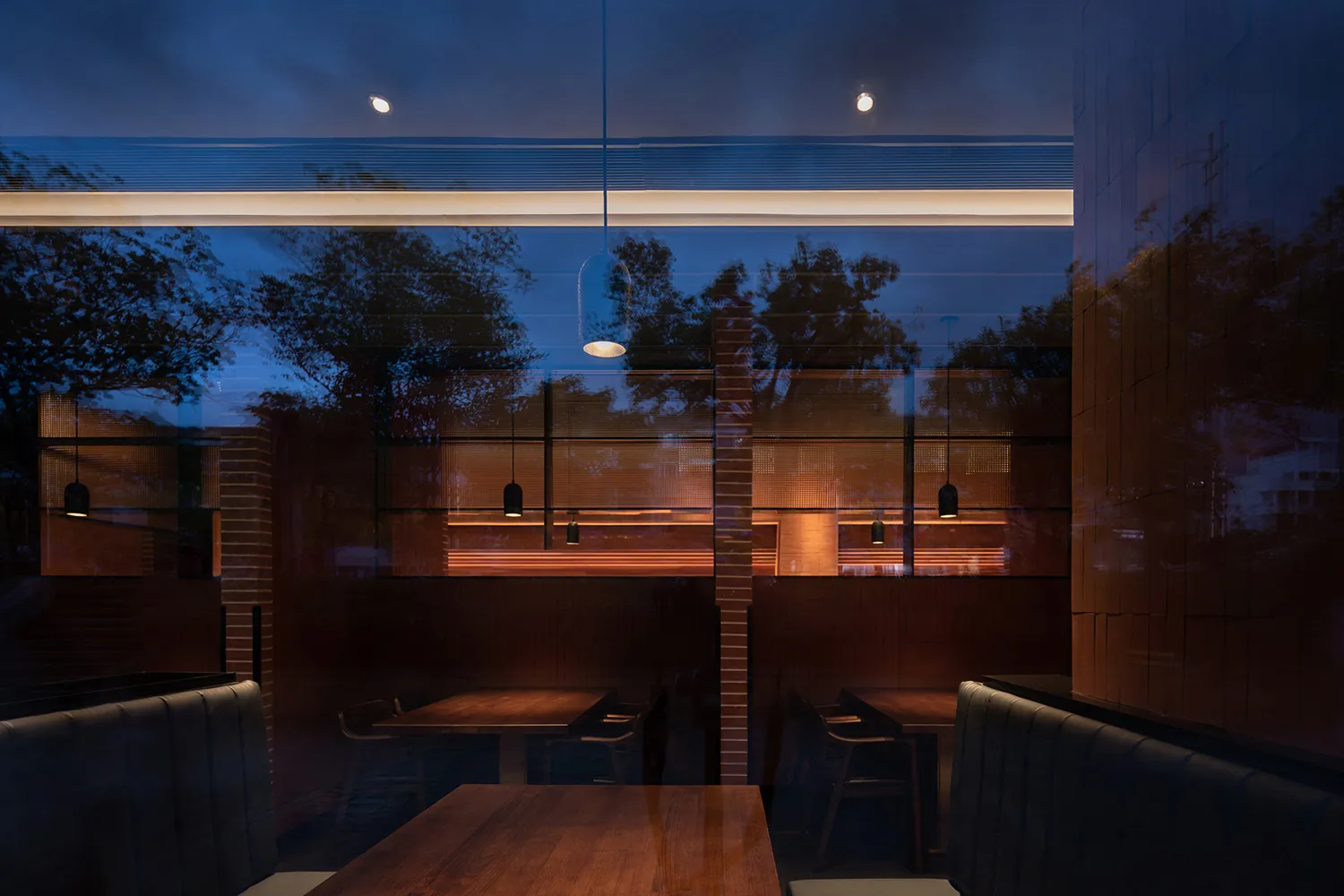 Interior view of a modern industrial restaurant featuring wooden furniture and large glass windows.