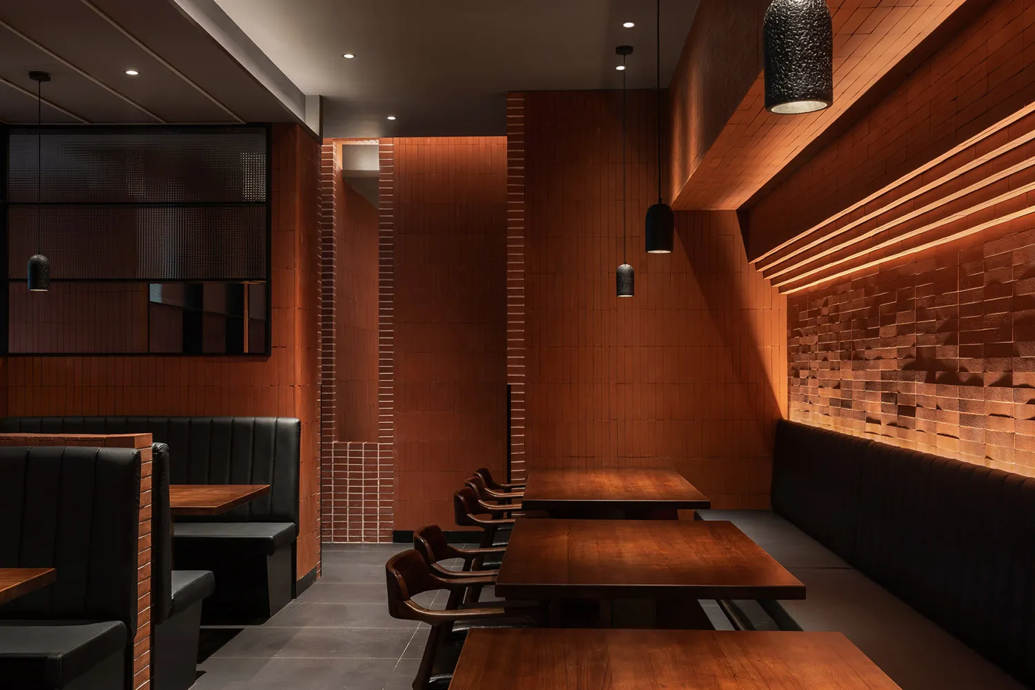 A cozy restaurant interior with brick tiles on the walls and wooden tables and chairs.