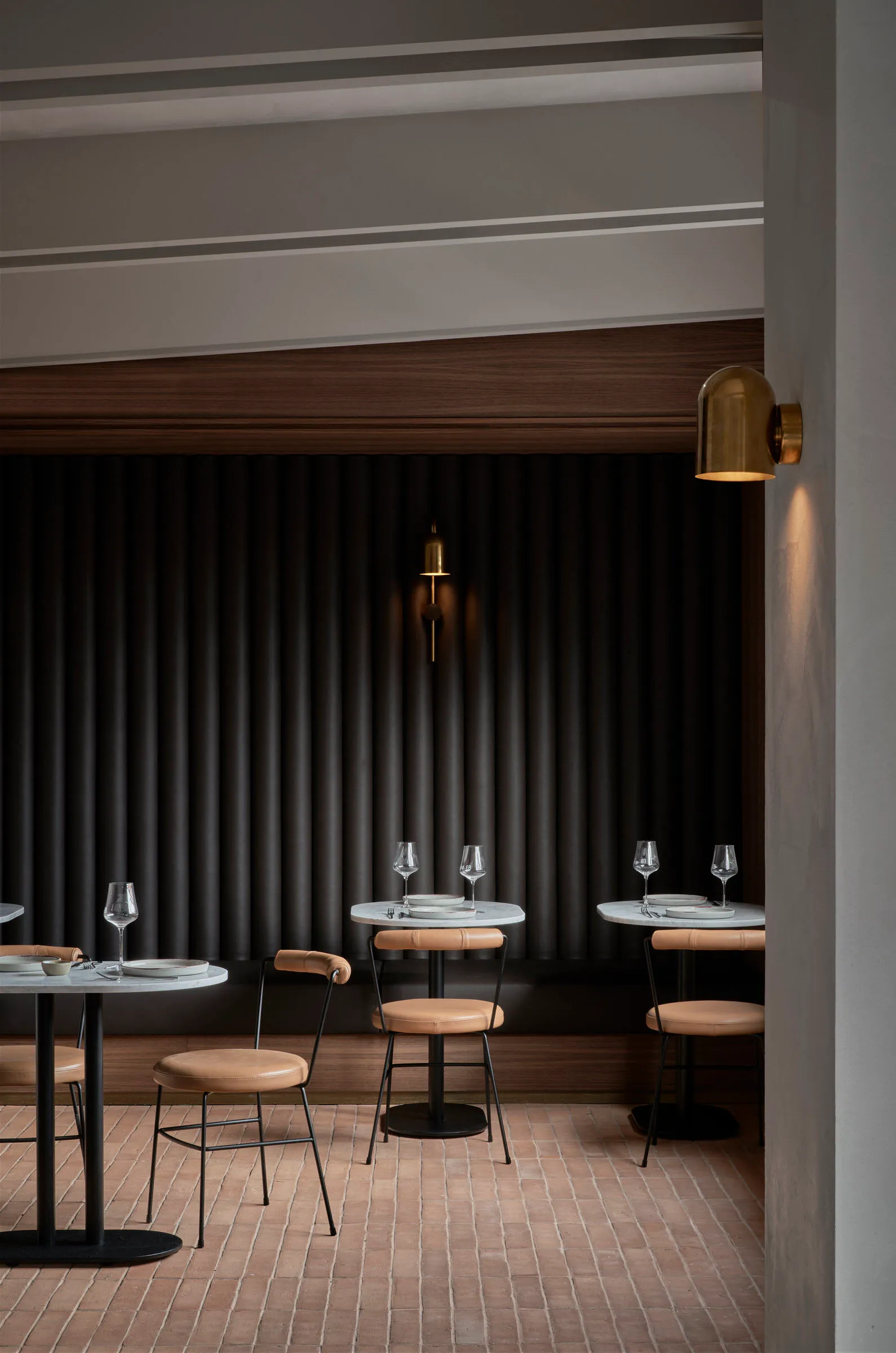 Modern dining room with metal tables, leather chairs, and wooden walls.