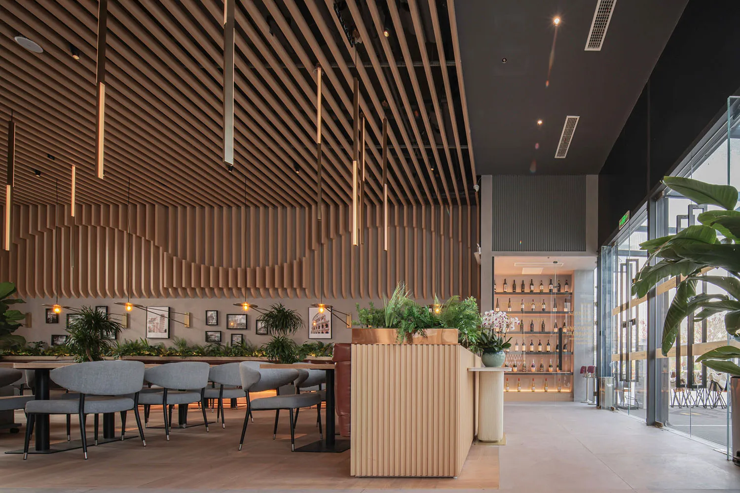 Modern interior of a cafe-bar with wooden slat walls, glass elements, and plants