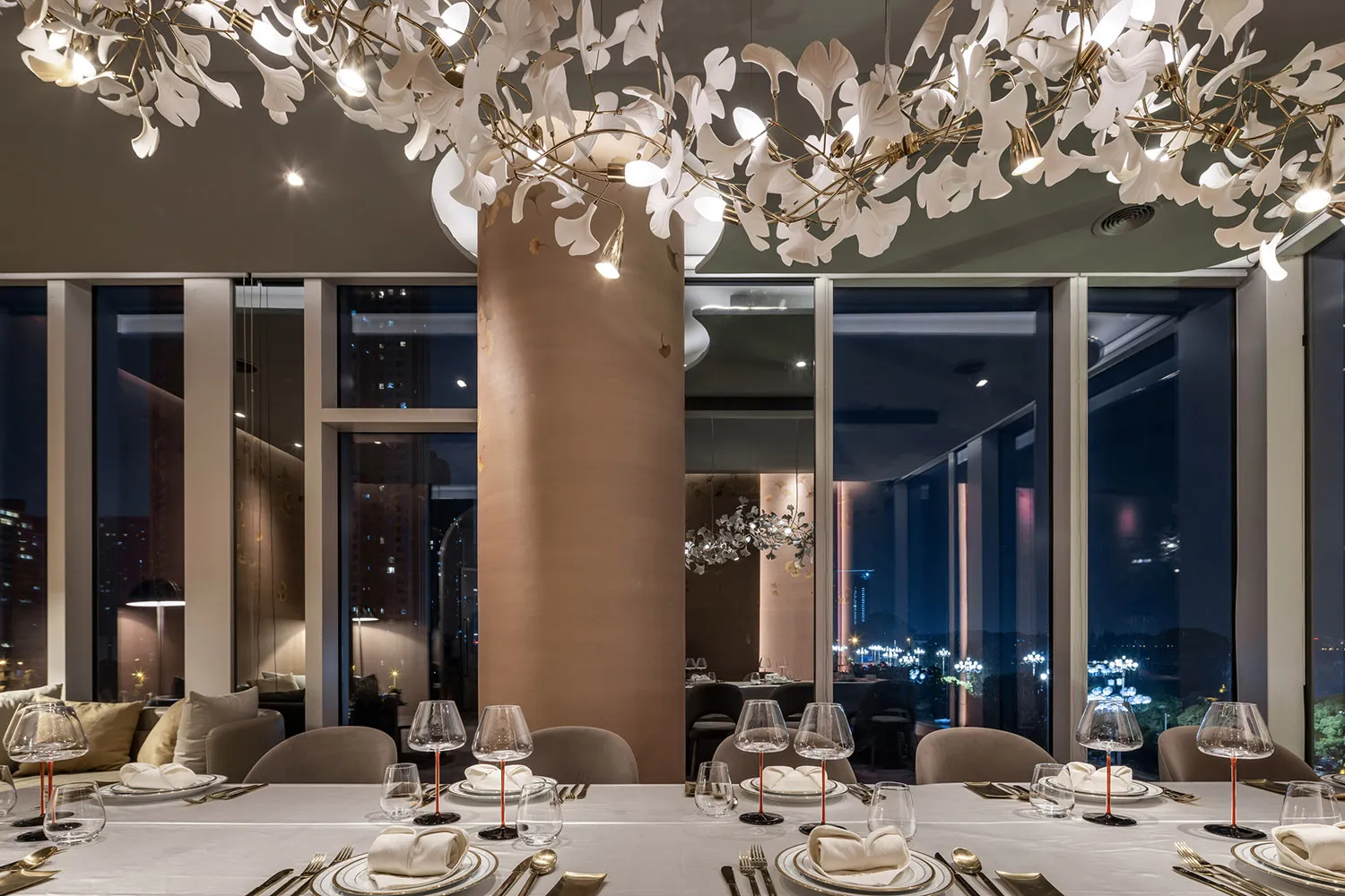 A modern restaurant interior featuring elegant lighting fixtures designed with glass and metal elements, complemented by fabr