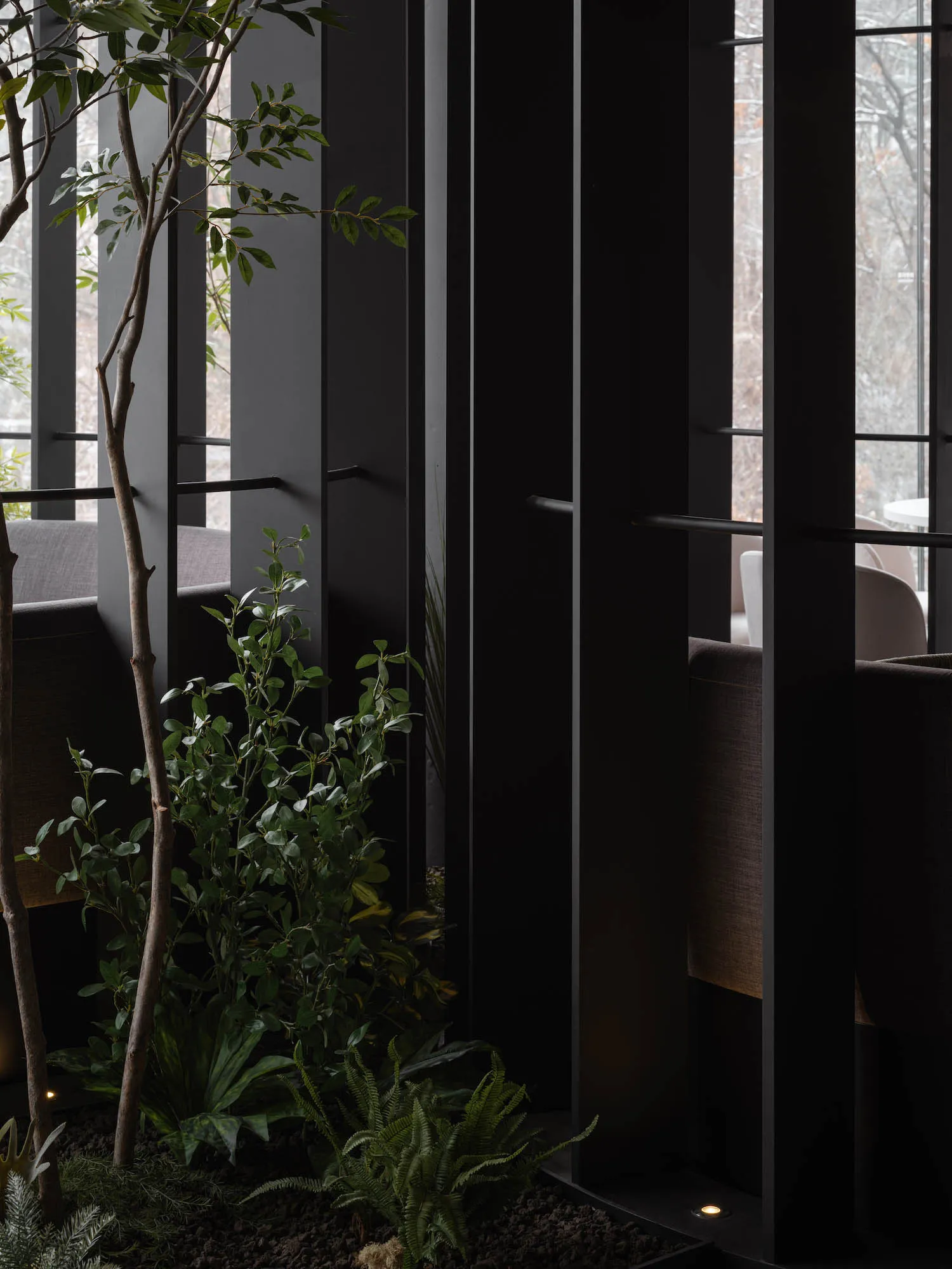 Modern, industrial-style restaurant interior with metal walls and green plants.