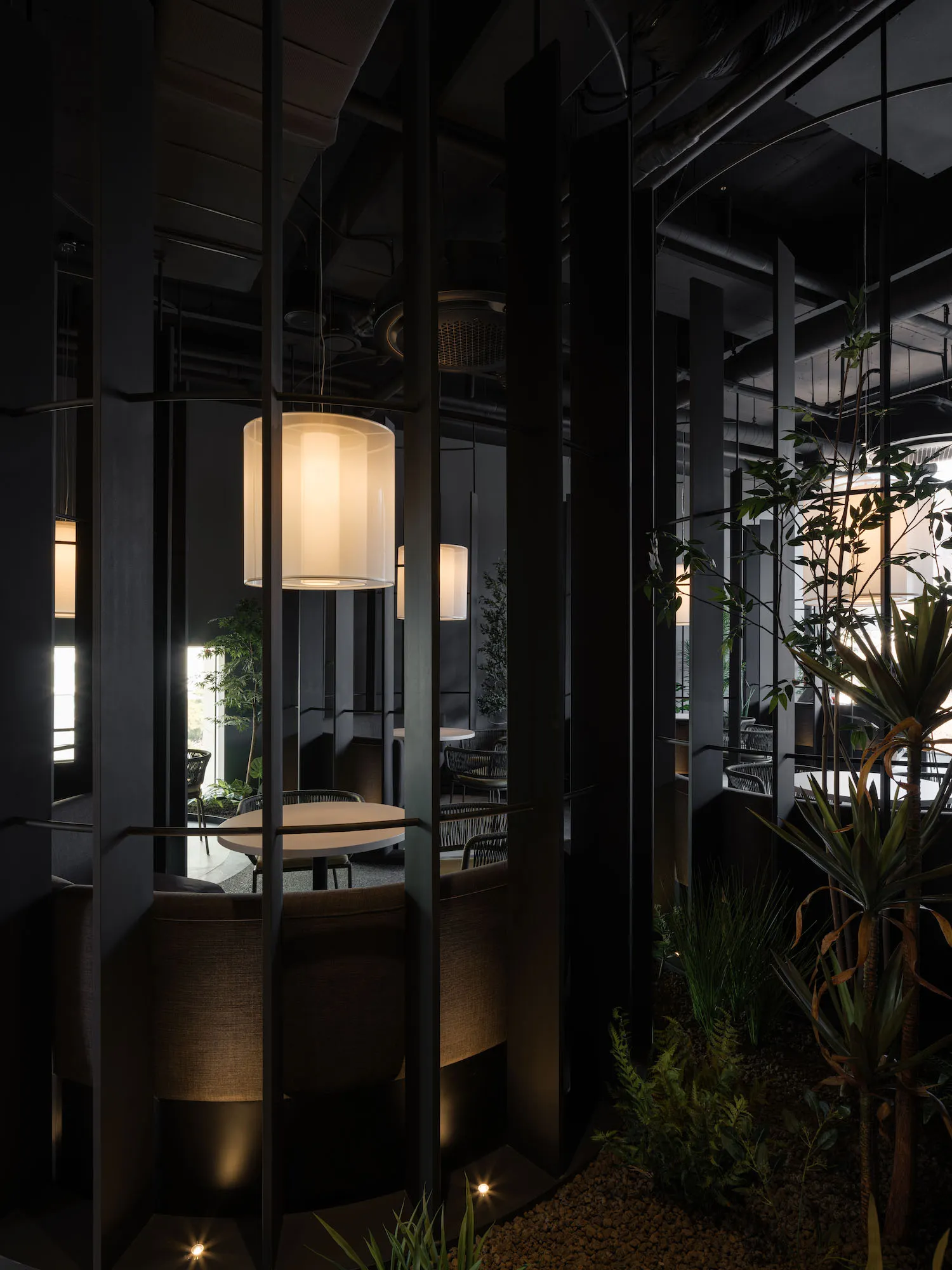 An interior view of a modern restaurant with concrete structures and hanging lamps.
