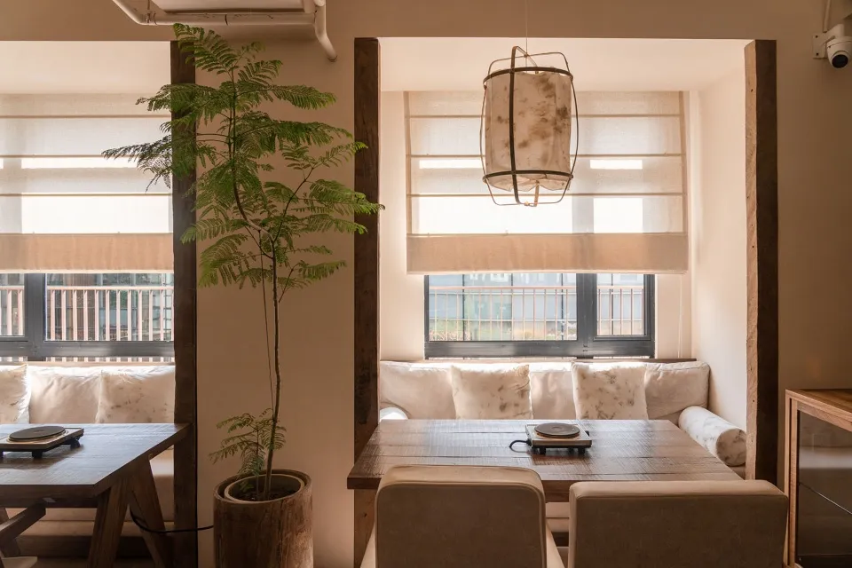 A cozy restaurant interior with wooden furniture, mixed materials, and a potted plant.