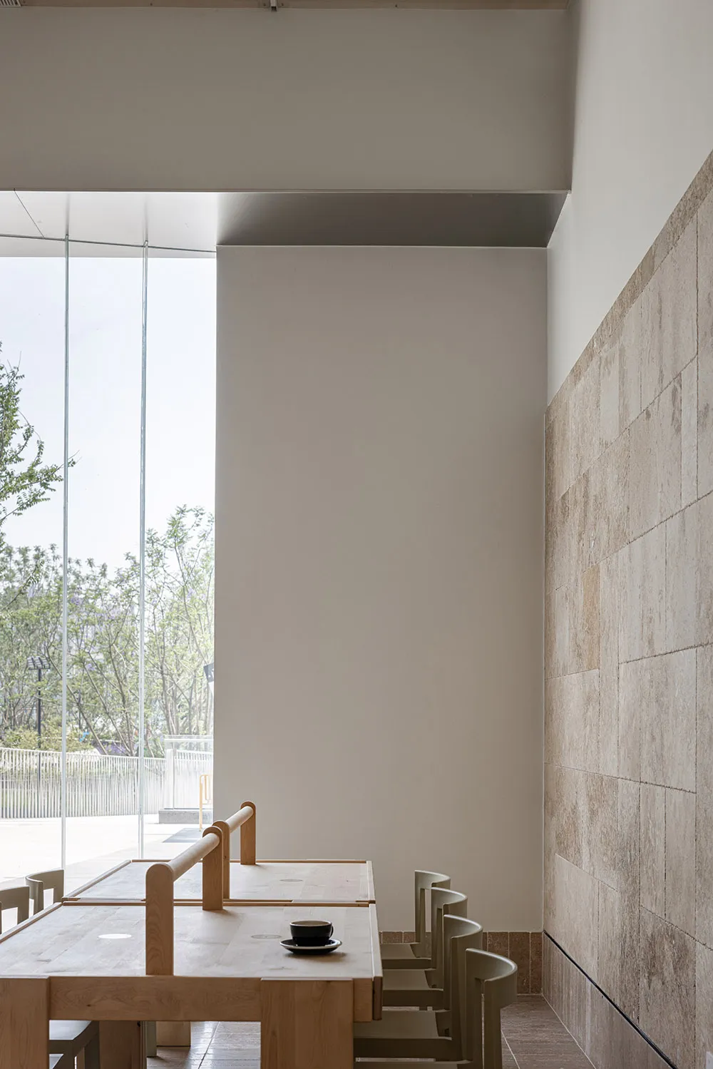 A minimalist cafe featuring wooden tables and stone walls.