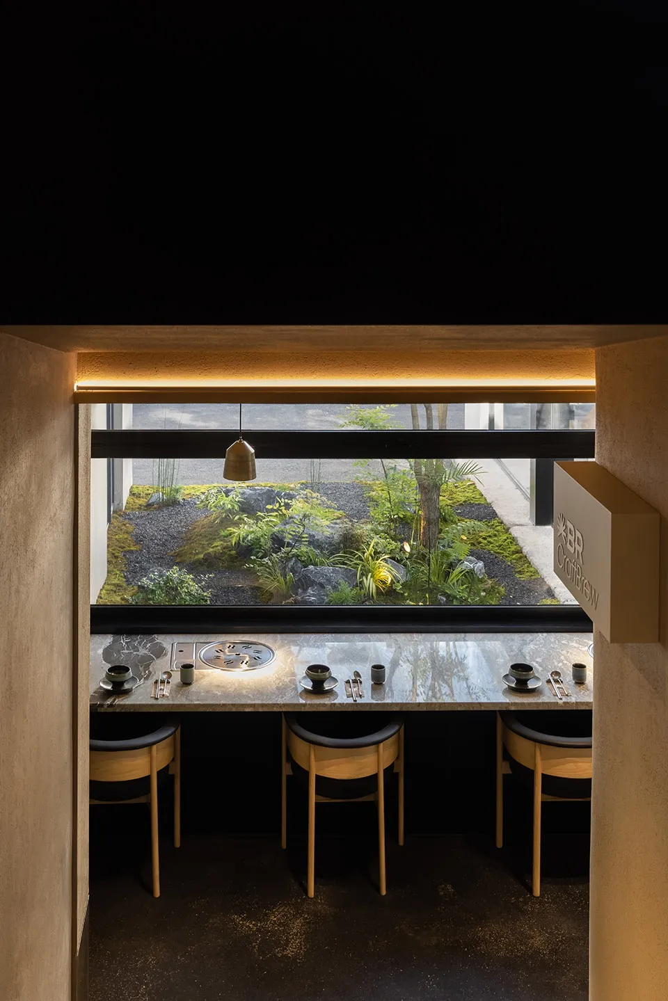 Modern restaurant interior featuring minimalist design with concrete, wood, and stone materials.