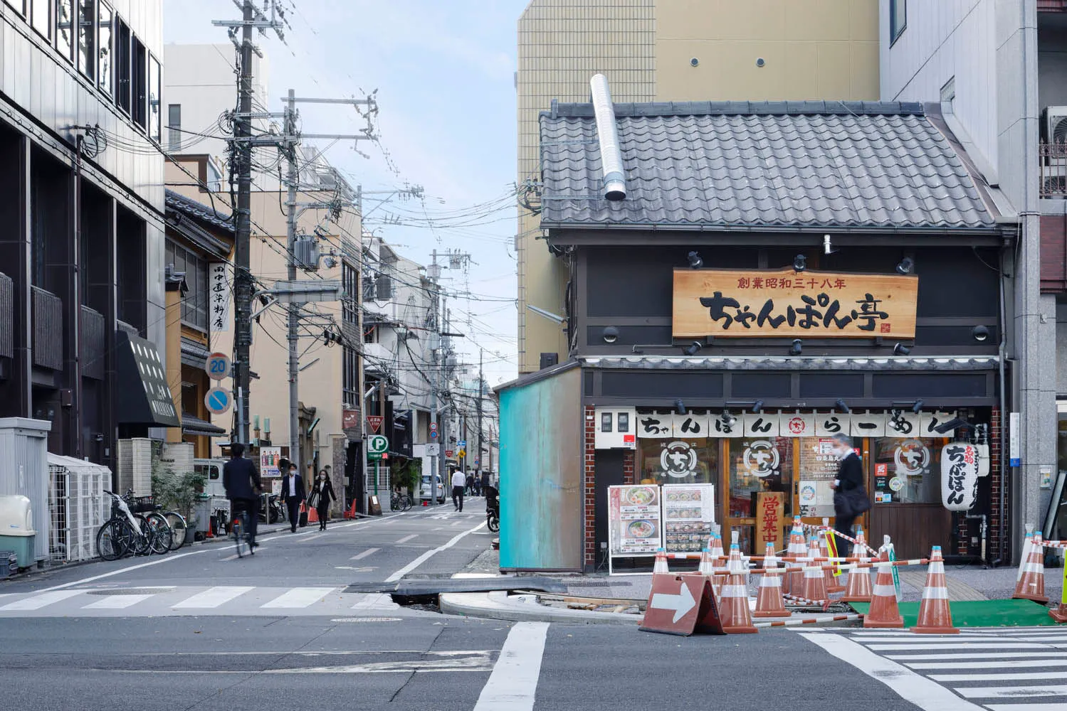 A photograph of an urban street featuring concrete buildings and power lines.