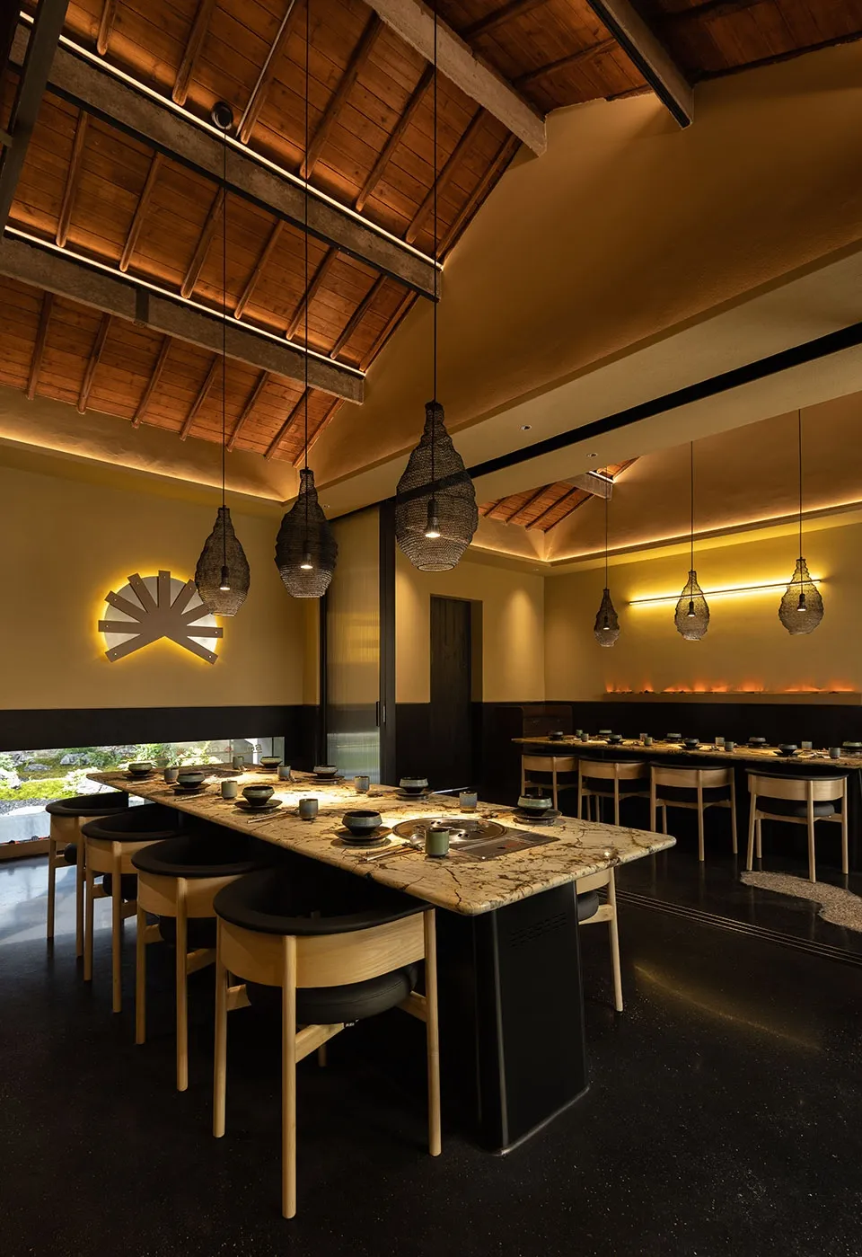 Japanese restaurant interior with black marble countertops and wooden elements, featuring hanging lights and traditional desi