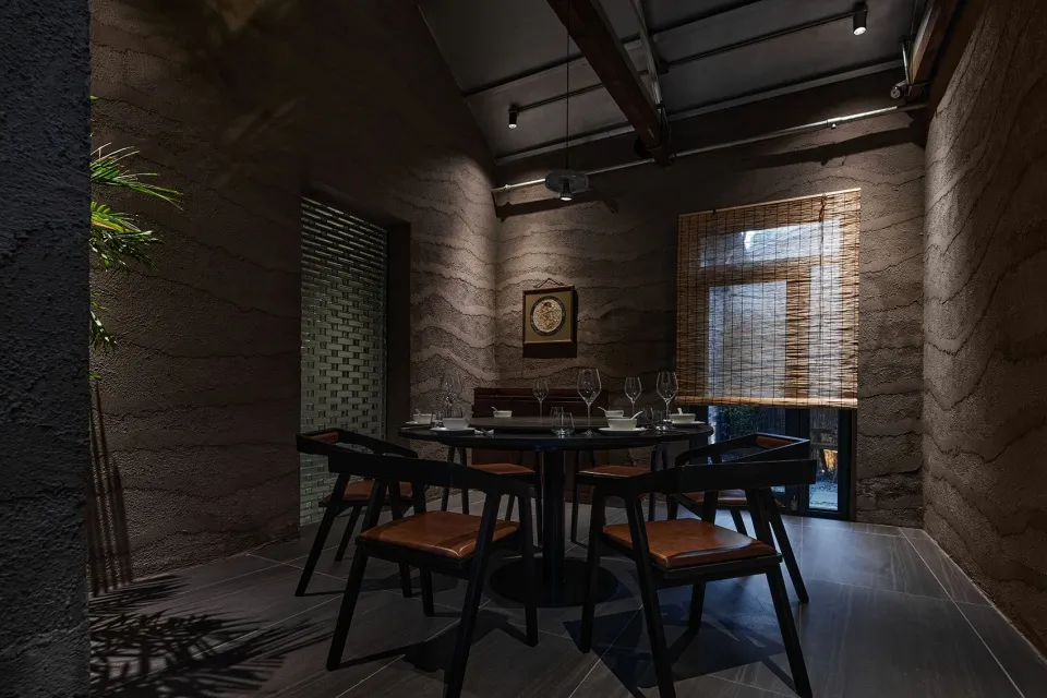 Industrial-themed restaurant interior with concrete walls, wooden chairs, and a round dining table.