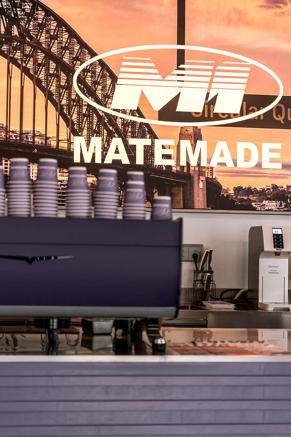 A coffee shop counter with purple and metallic finishes, featuring a modern design with a concrete backdrop.