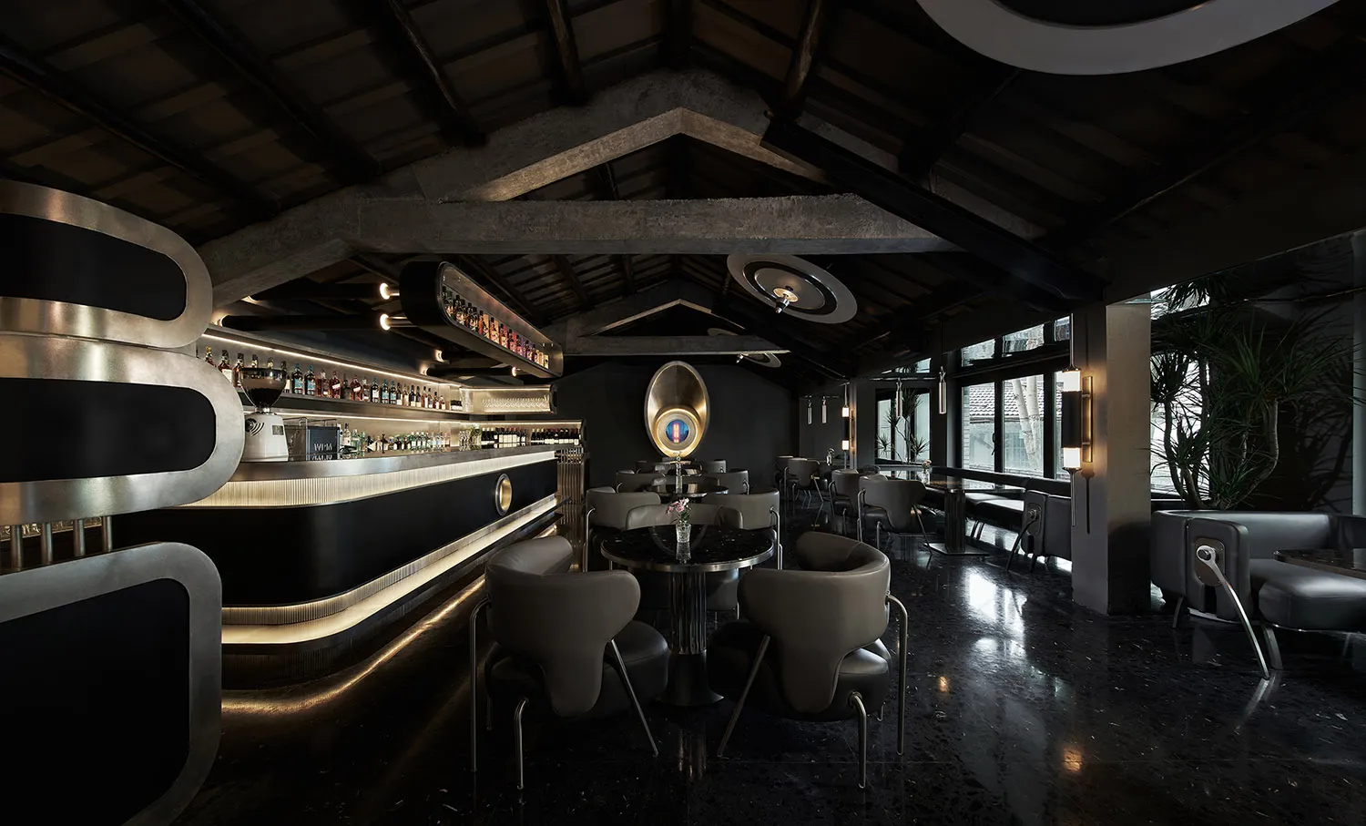A modern industrial coffee shop bar with a sleek black design, featuring metal and concrete materials, and large windows with