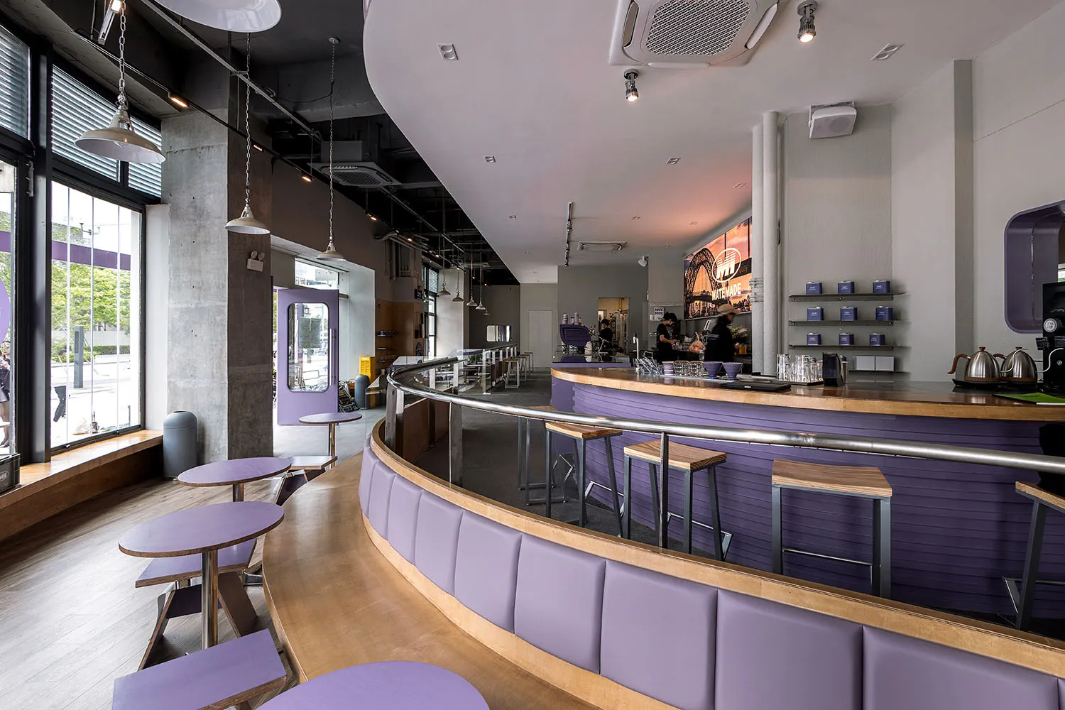 A modern coffee shop interior with purple accents and wooden finishes.