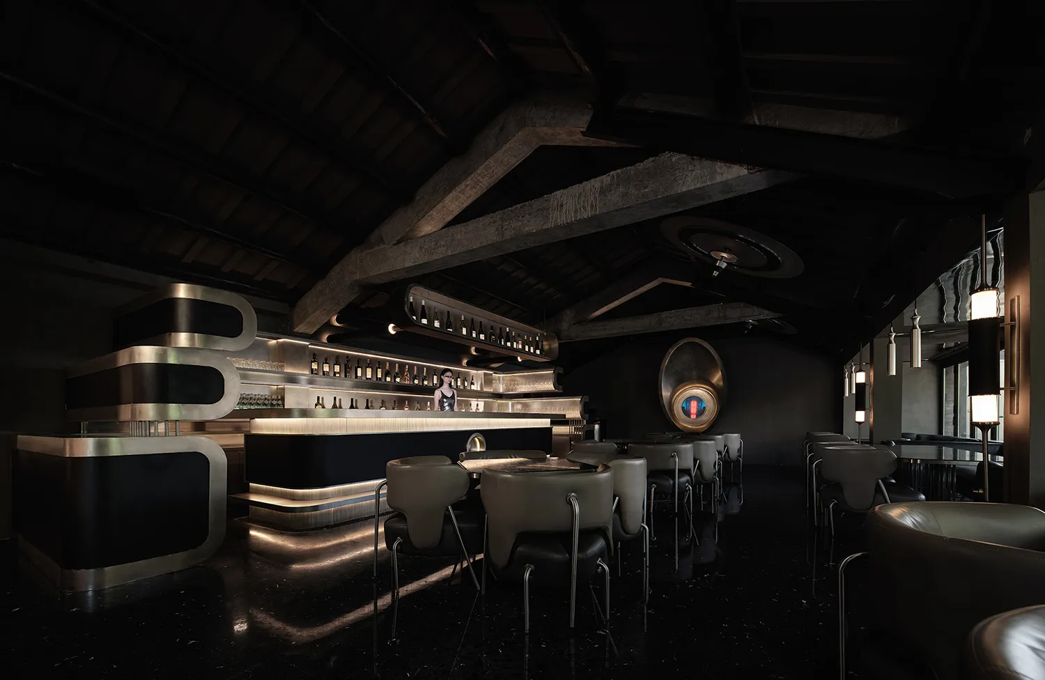 A dimly lit industrial restaurant bar with black decor and modern seating.