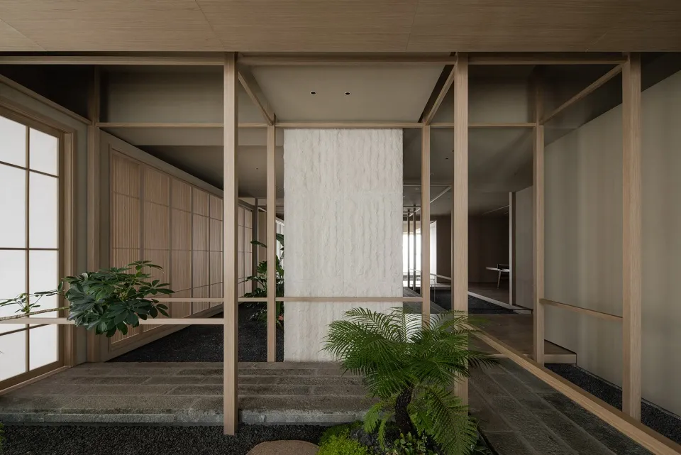 Minimalist residential lobby featuring wooden columns, stone floor, and glass partitions