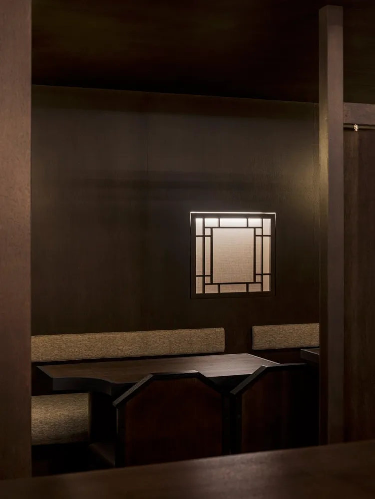 Dark wooden restaurant booth with a lit window panel