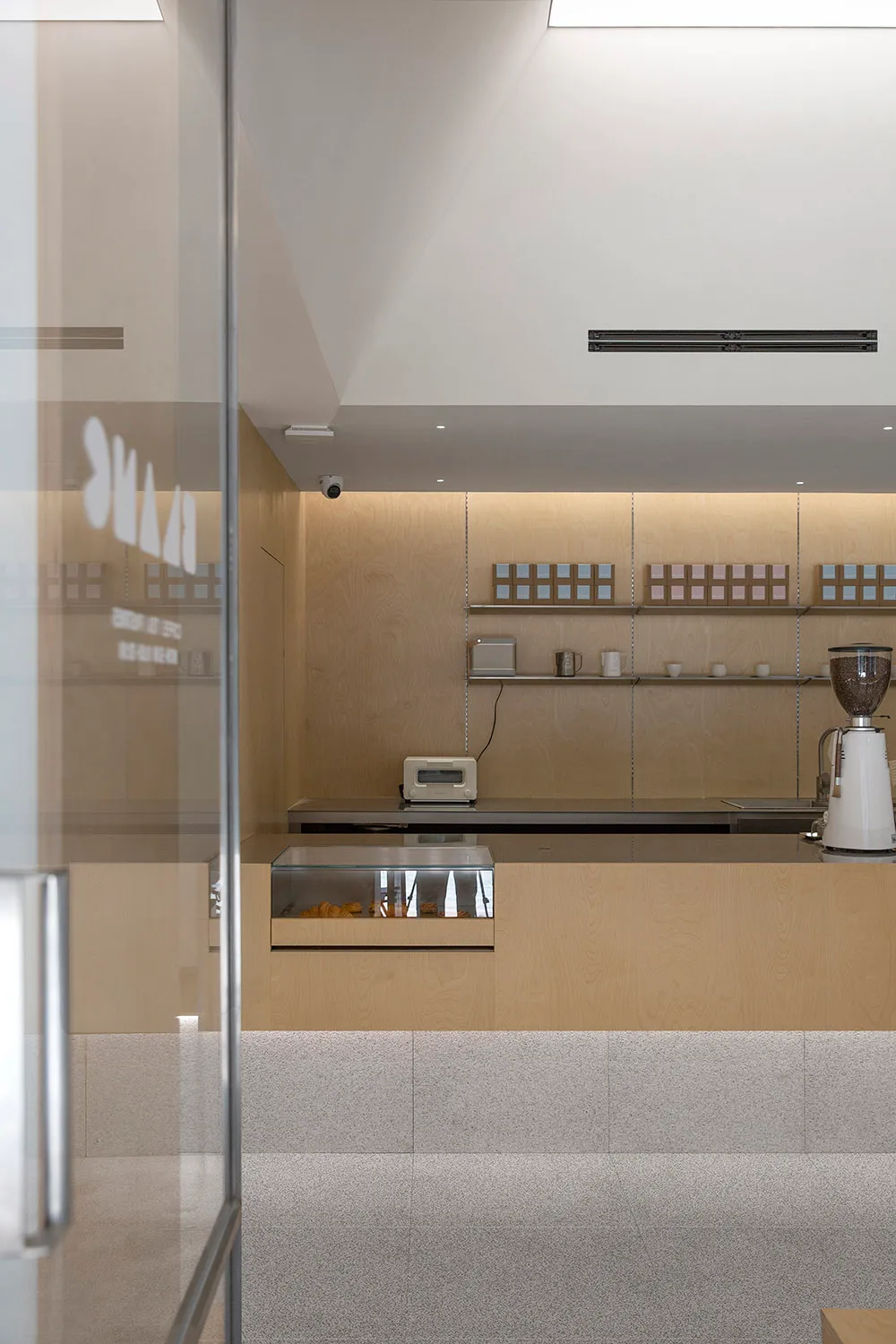 A minimalist coffee shop interior with steel, wood, and glass materials.