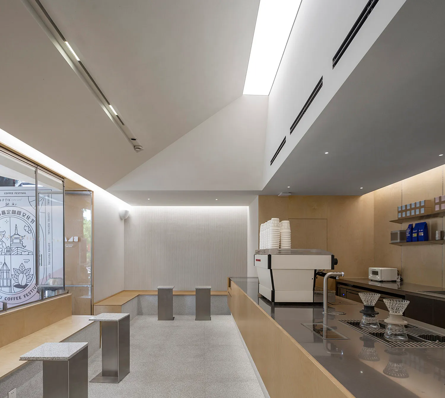 A minimalistic coffee shop interior predominantly made of white concrete materials, featuring sleek lines and modern design e