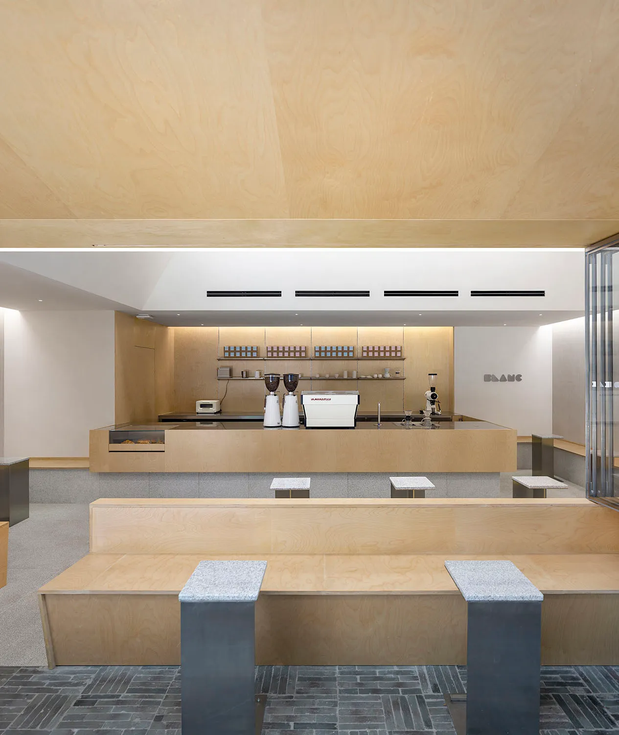 Modern minimalist coffee shop interior with wood, concrete, and metal elements.