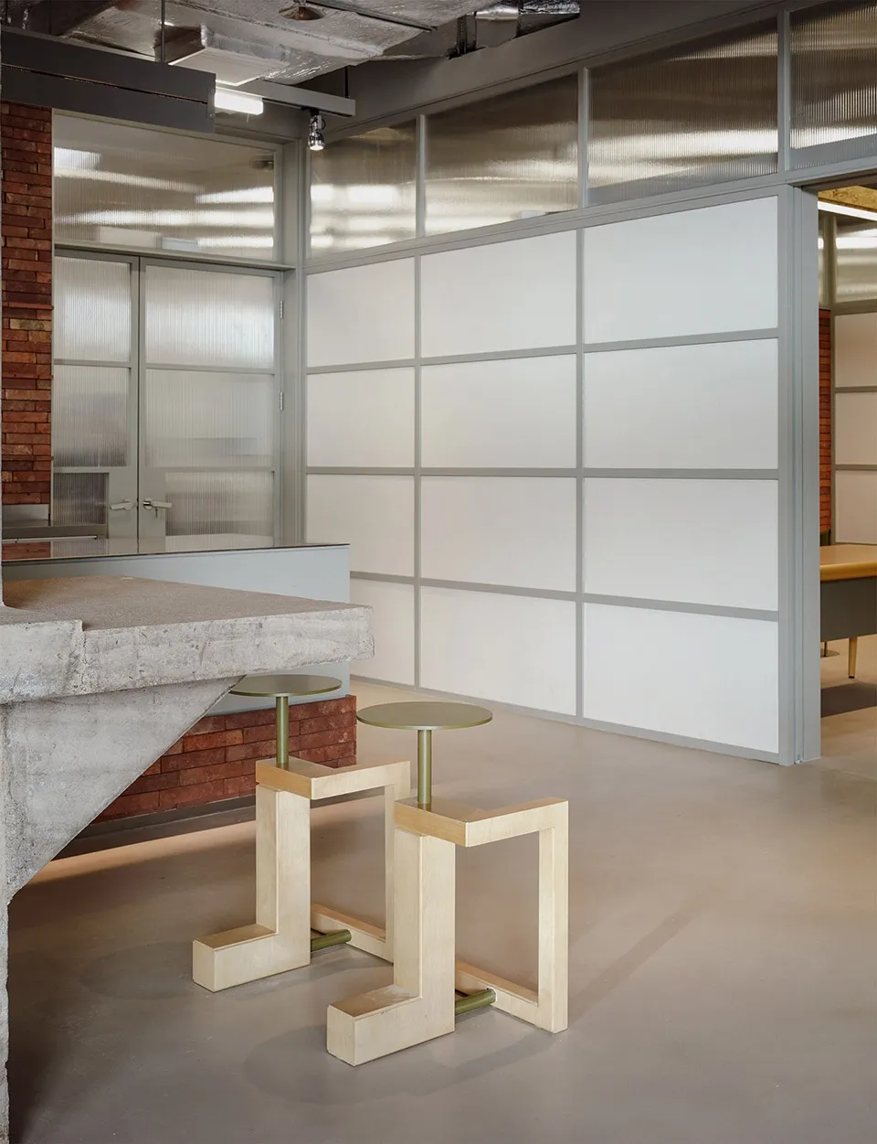 A modern office space featuring concrete, glass, and metal elements.