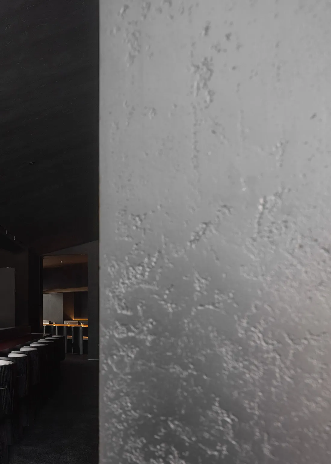 Close-up of a textured concrete wall inside an industrial-style restaurant.