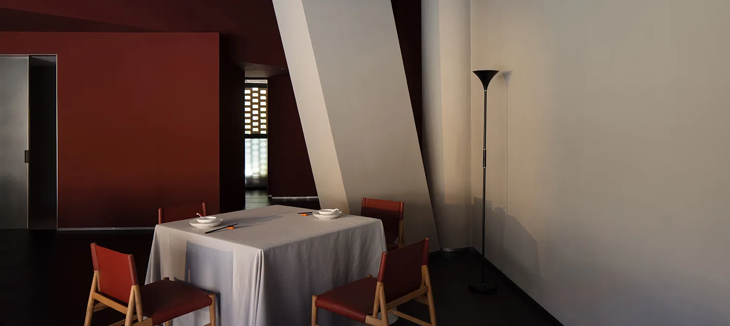 Modern minimalist dining room with white tablecloth, red chairs, and floor lamp in a contemporary space.