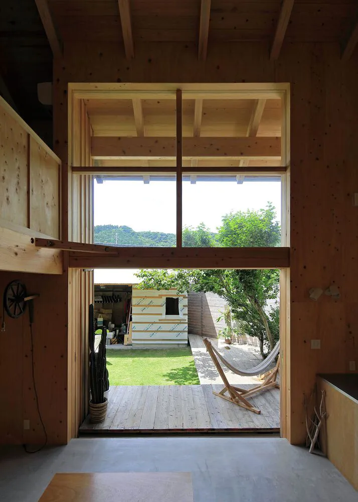 A modern residential home with a wooden exterior features a spacious backyard with a hammock and deck.