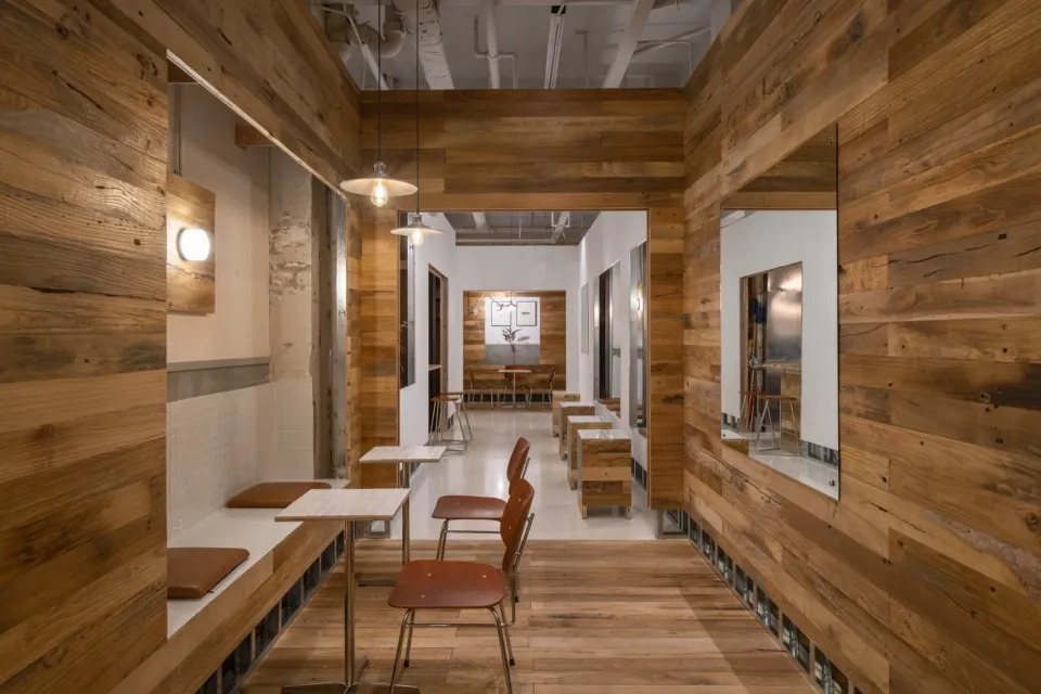 Interior of a cafe with wooden walls, tables, and chairs.