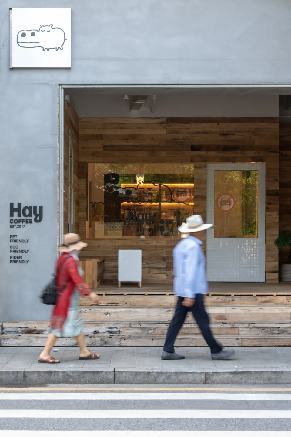 A modern coffee shop exterior featuring wooden paneling, concrete, and tile.