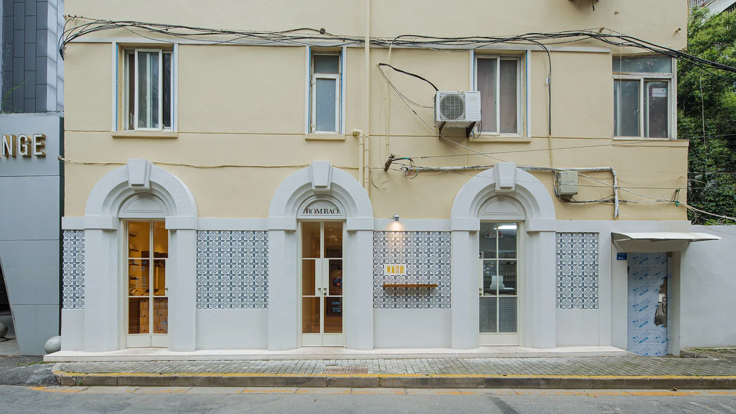 A retail shop front with tiles, concrete, and an air conditioner.
