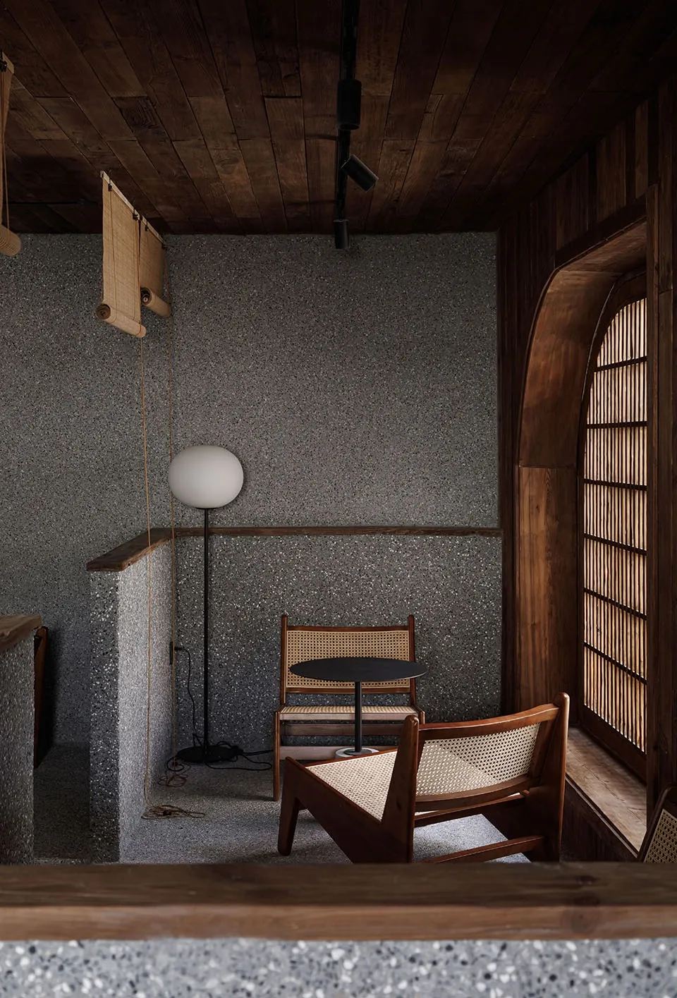 Industrial-style cafe featuring concrete walls, wooden furniture, and a round table with two chairs.