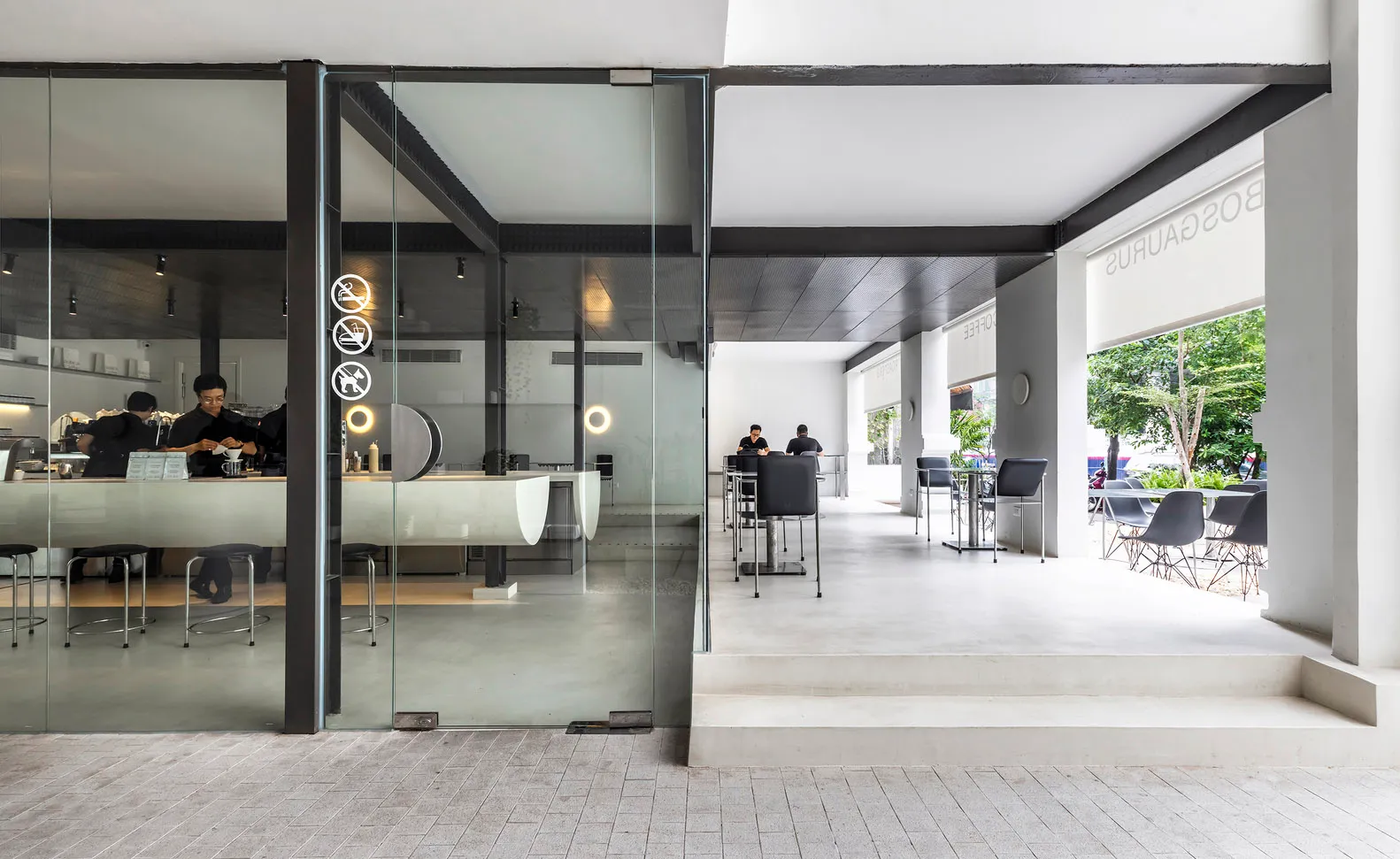 A modern coffee shop with concrete and glass materials, featuring a clean and minimalist design.