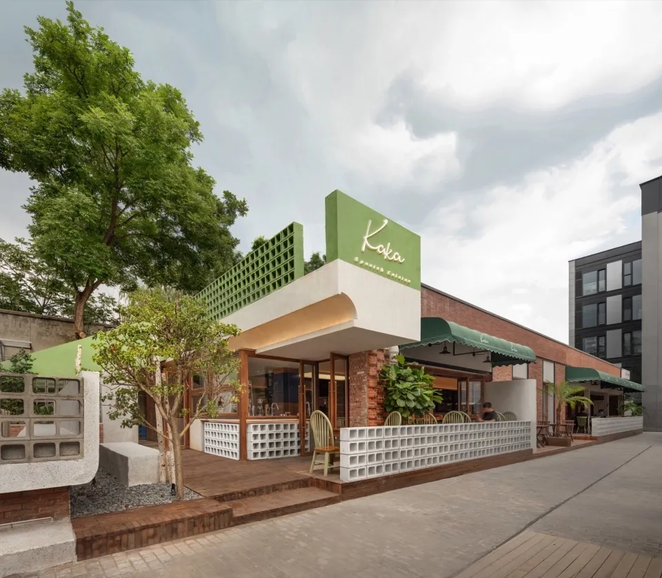 Modern restaurant with green-themed brick and concrete exterior.