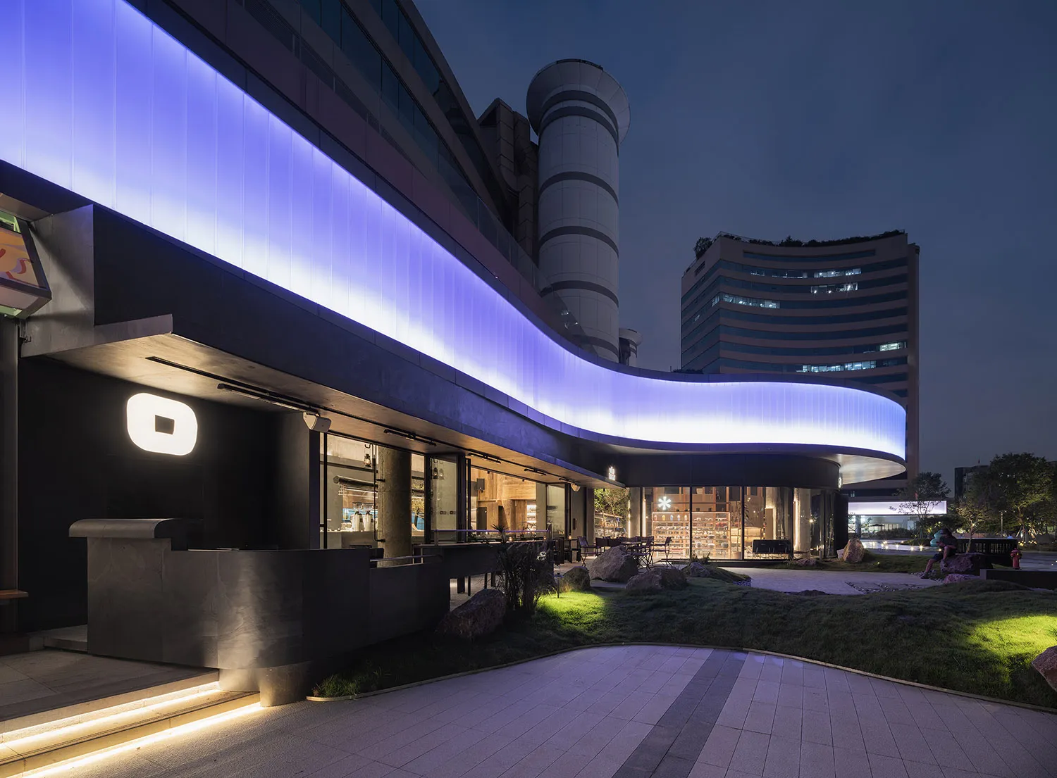 A minimalist retail storefront featuring concrete elements at night.