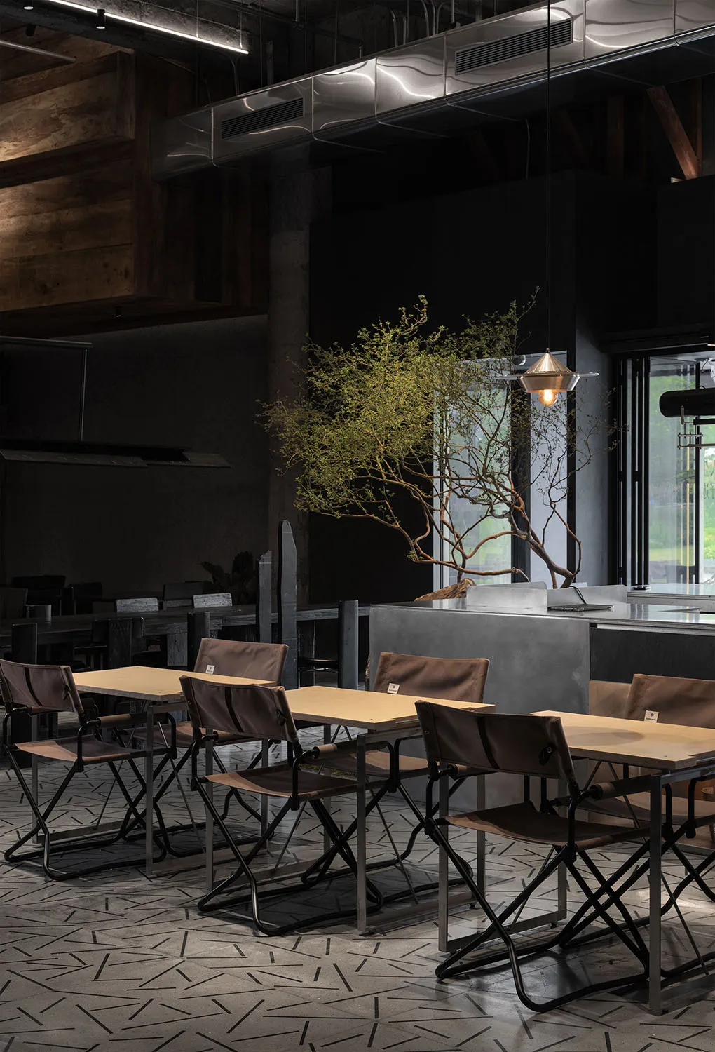 Industrial-style restaurant interior with metal accents, concrete walls, and wooden tables and chairs.