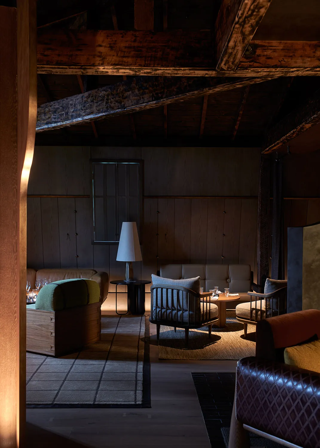 舒適的工業風客廳，搭配木樑、深色木質家具與柔和燈光，設有舒適的座位區