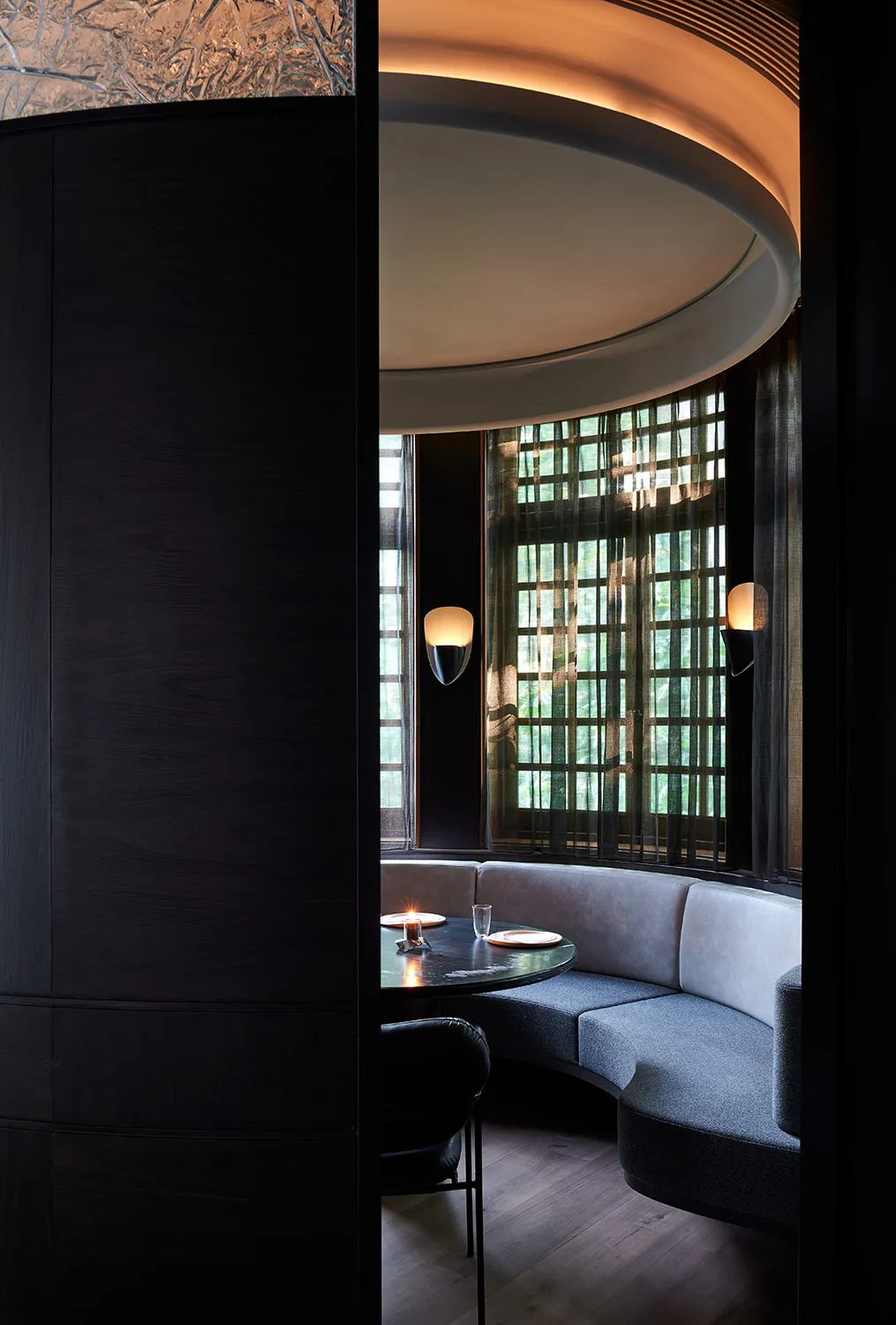 Circular booth seating area in a modern restaurant with concrete flooring and upholstered cushions.